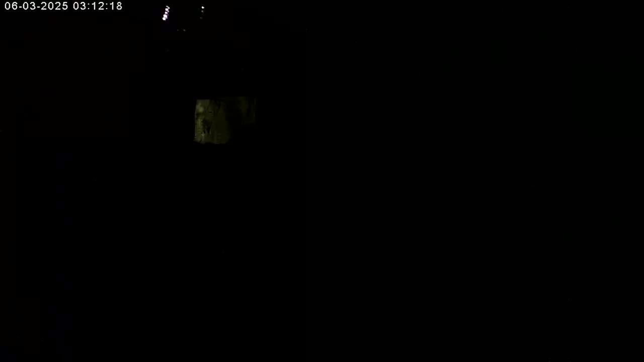 A mostly dark image shows a faintly illuminated, indistinct object in the upper-center.