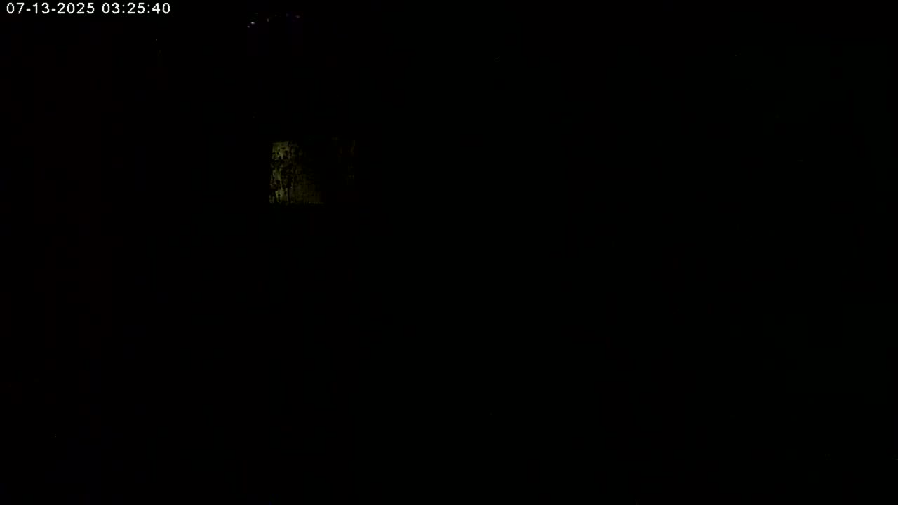 A very dimly lit, possibly nighttime scene shows a small, indistinct area of light in the upper left.