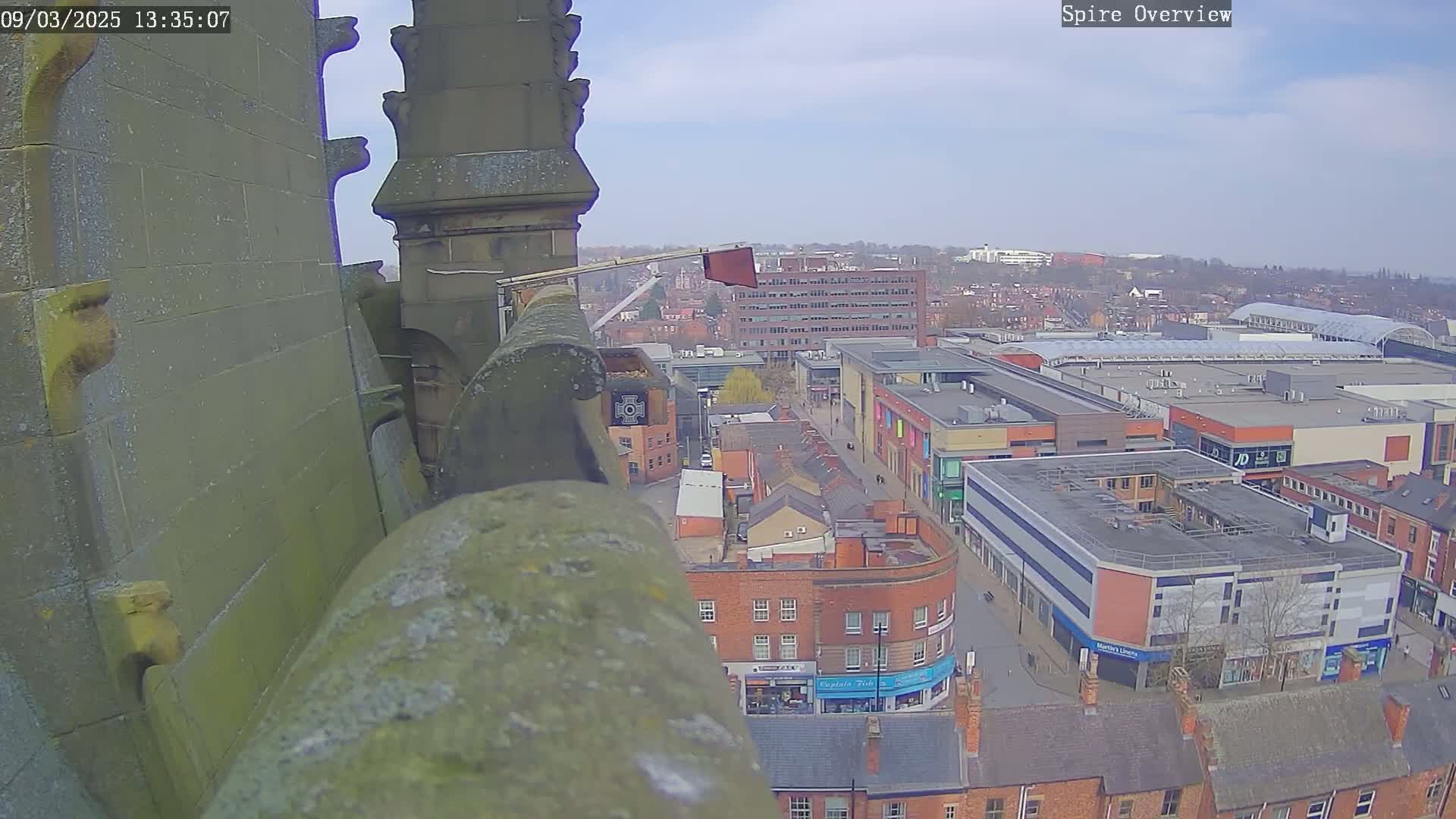 A high-angle view from a stone structure shows a city under a partly cloudy sky.