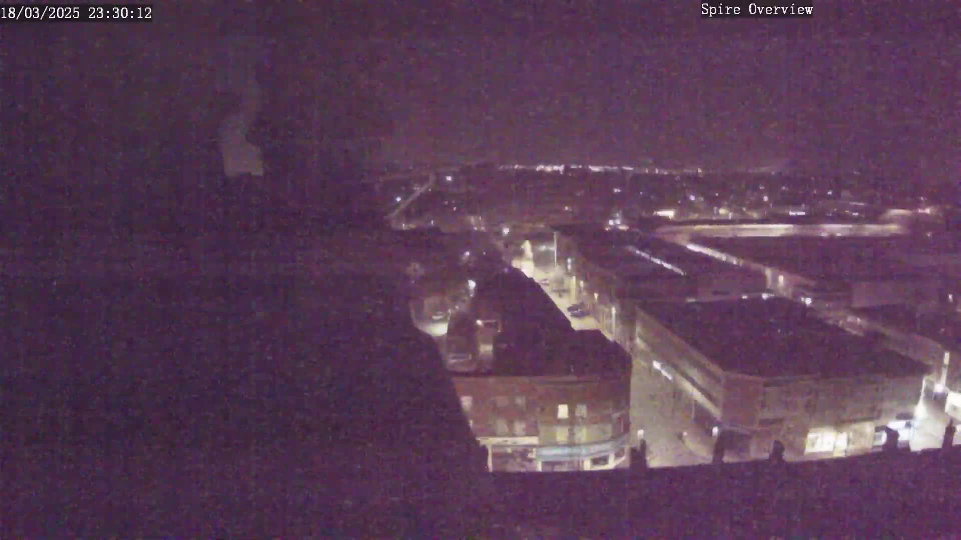 A nighttime, high-angle view shows a city with dimly lit streets and buildings.
