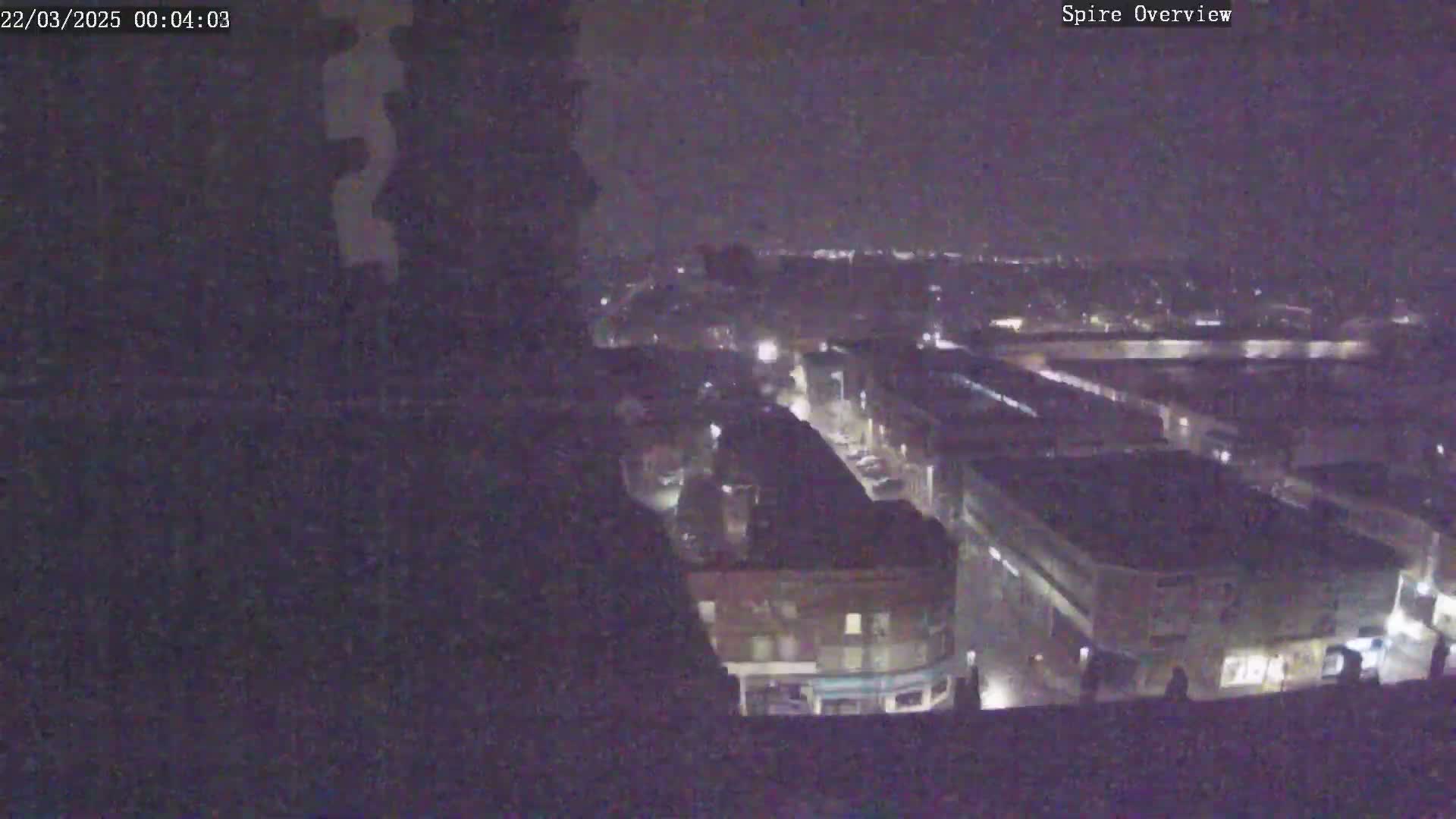 A nighttime, high-angle view shows a city with dimly lit streets and buildings.