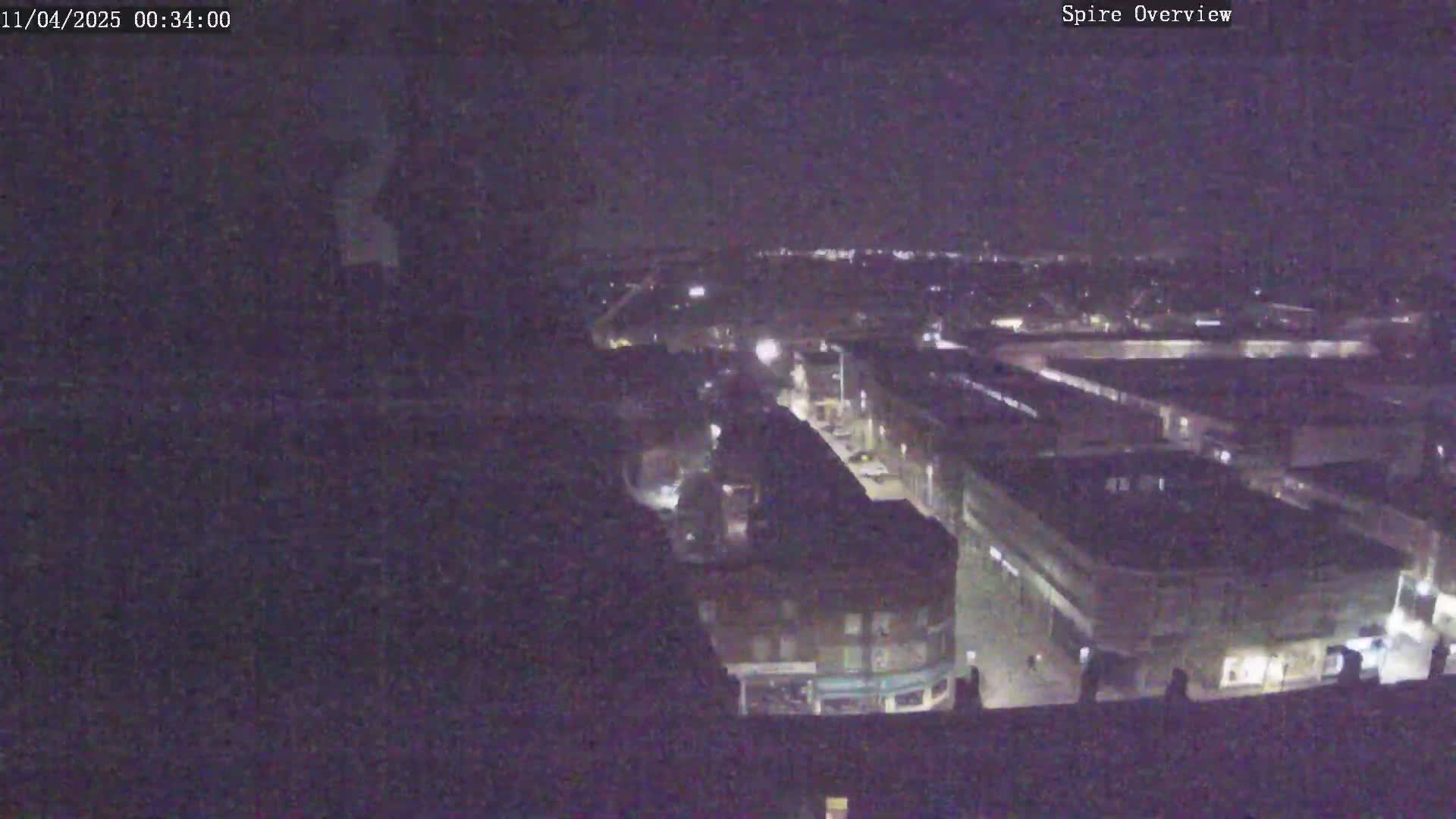A nighttime, high-angle view shows a city block with buildings and streets illuminated by sparse streetlights.