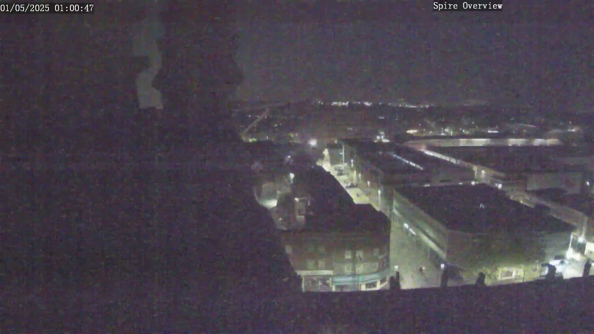 A nighttime, high-angle view shows a city block with buildings and streets faintly illuminated.