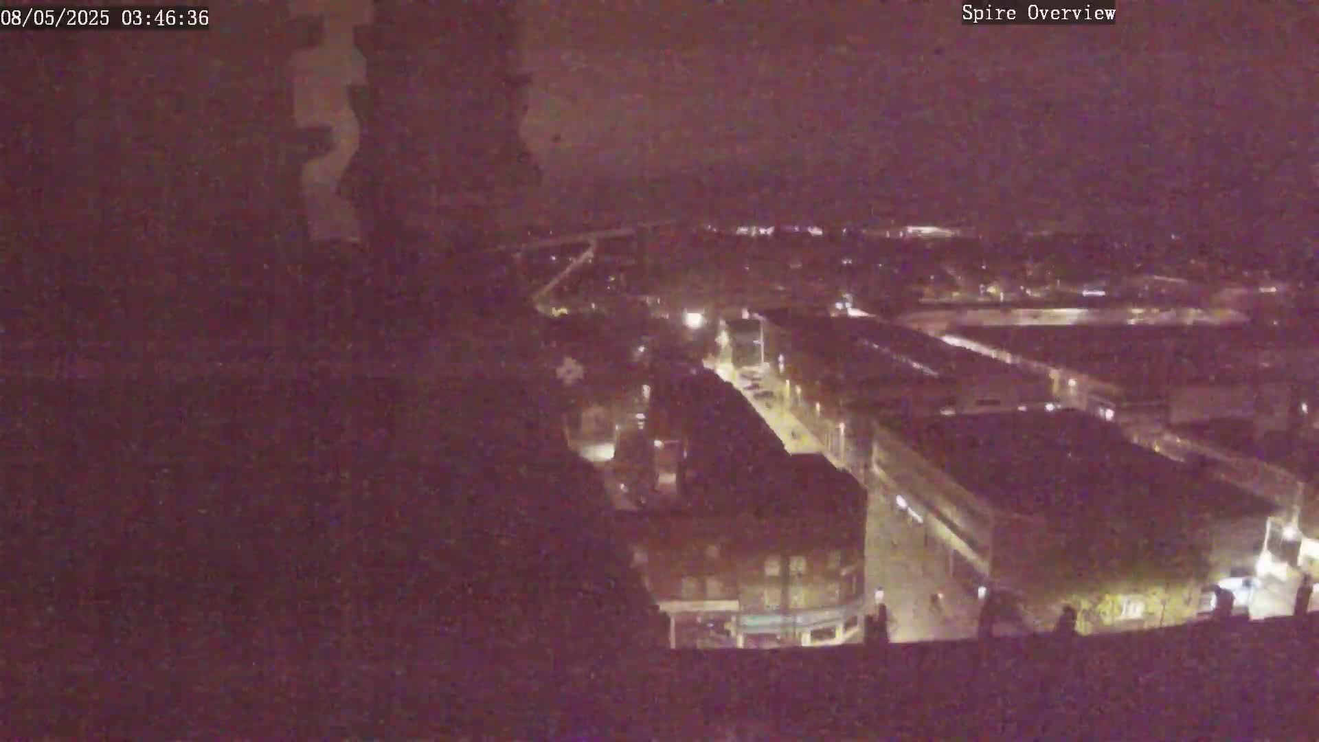 A nighttime aerial view shows a city with illuminated streets and buildings.