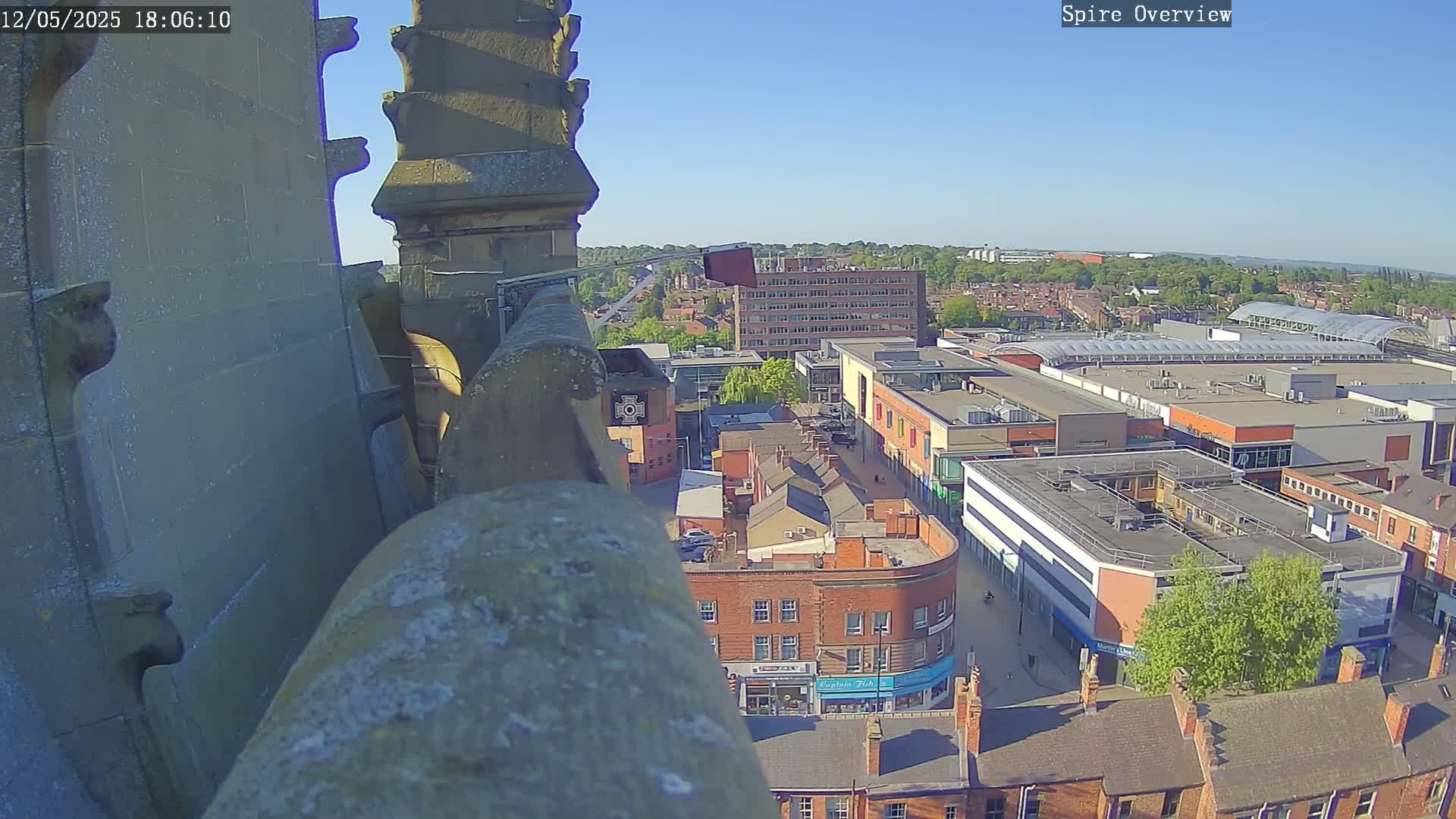 A high-angle, sunny view from a spire shows a town square and shopping center below.