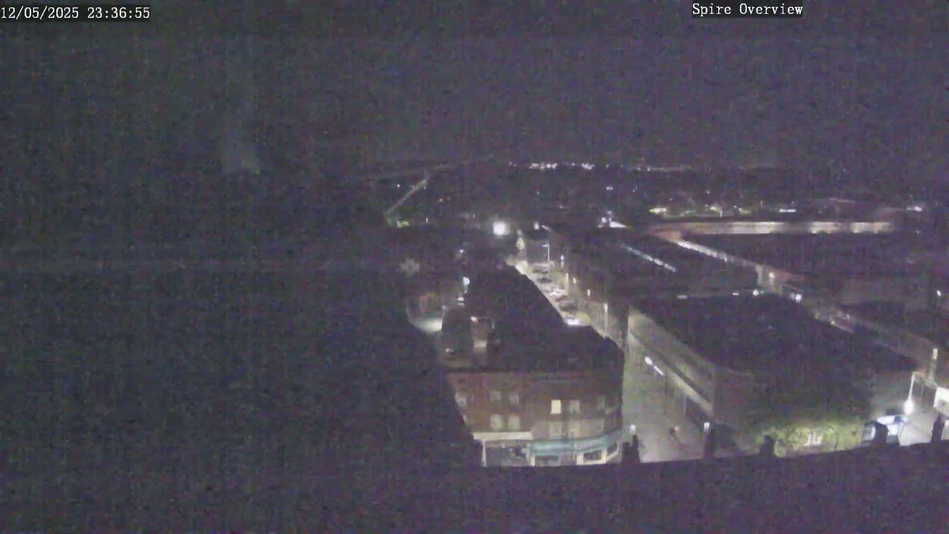 A nighttime, high-angle view shows a city with dimly lit buildings and streets.