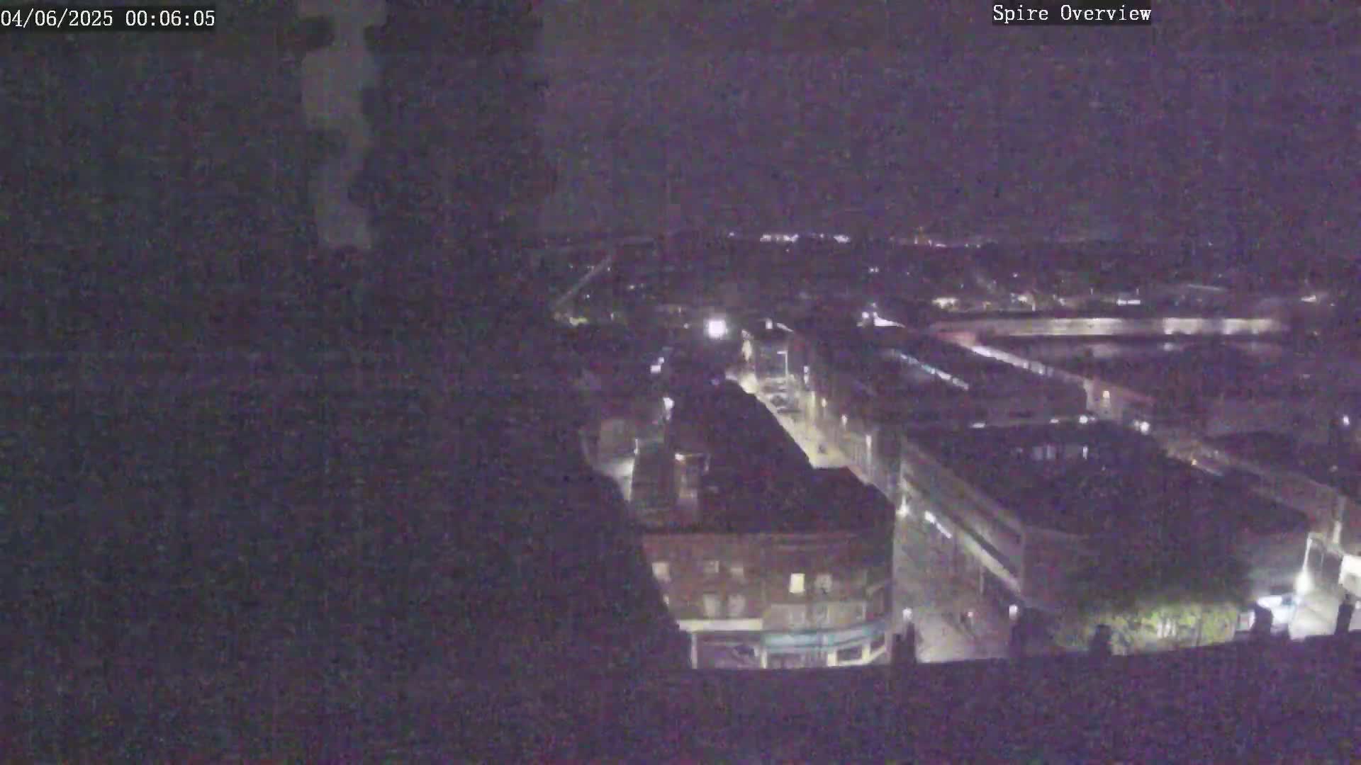 A nighttime, high-angle view shows a city with dimly lit buildings and streets.