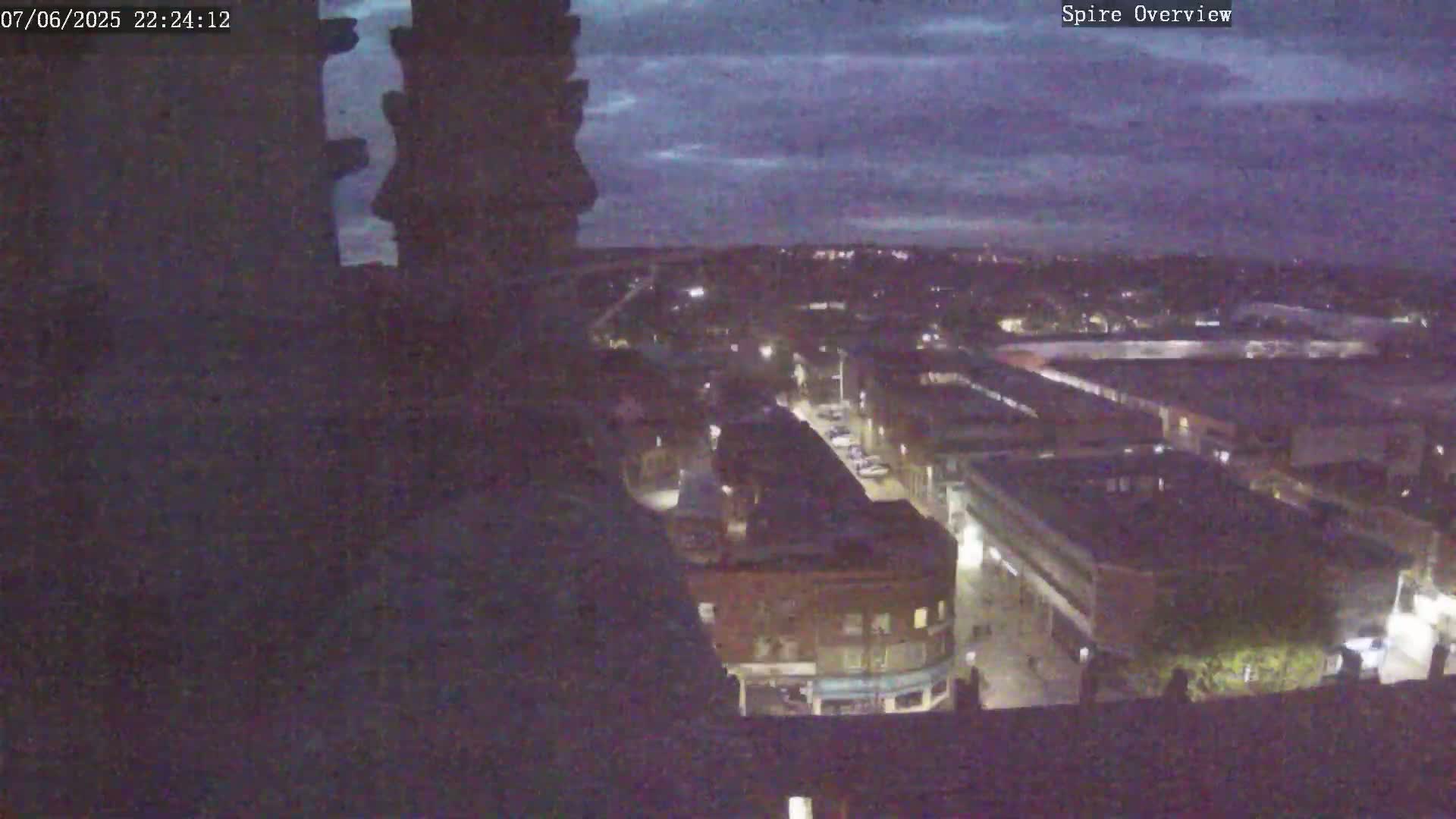 A nighttime, high-angle view shows a city under a dusky sky.