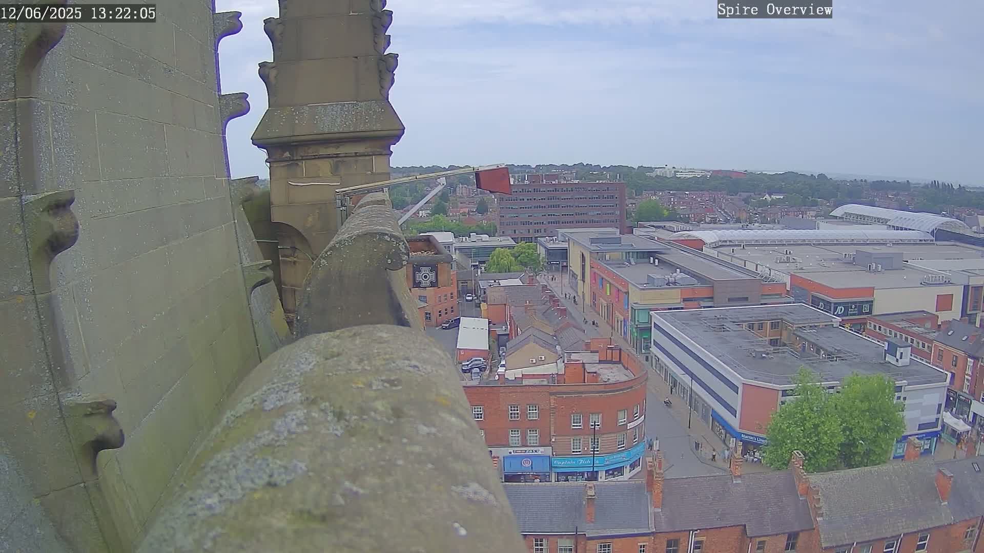 A high-angle view from a stone structure shows a town under a partly cloudy sky.