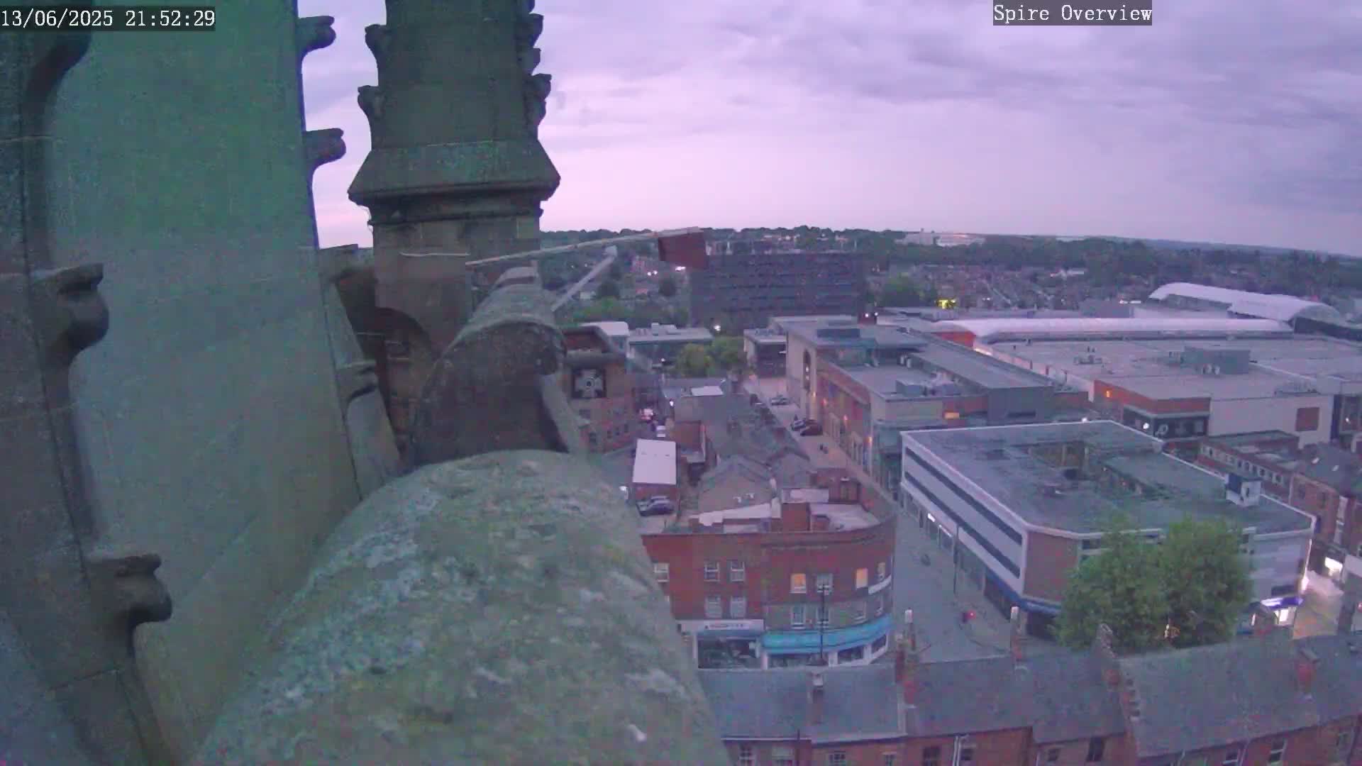 A high-angle view from a stone spire shows a town at twilight under a cloudy sky.