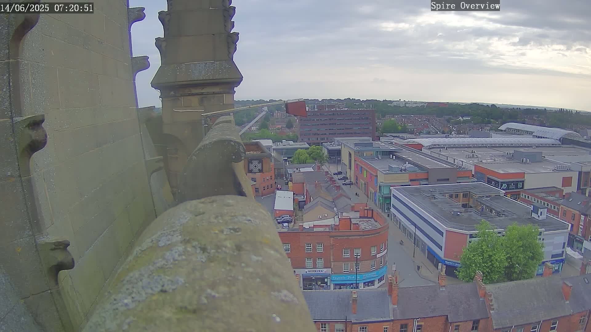 A high-angle view from a stone spire shows a town at twilight under a cloudy sky.