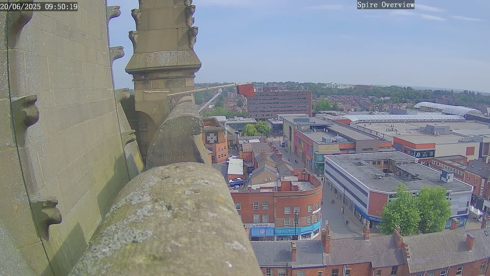 A high-angle view on a sunny day shows a stone structure overlooking a town square and a shopping center.