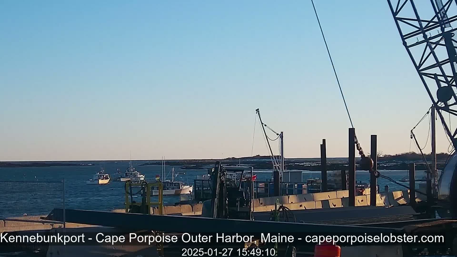 Several fishing boats are in a harbor under a clear, light blue sky.