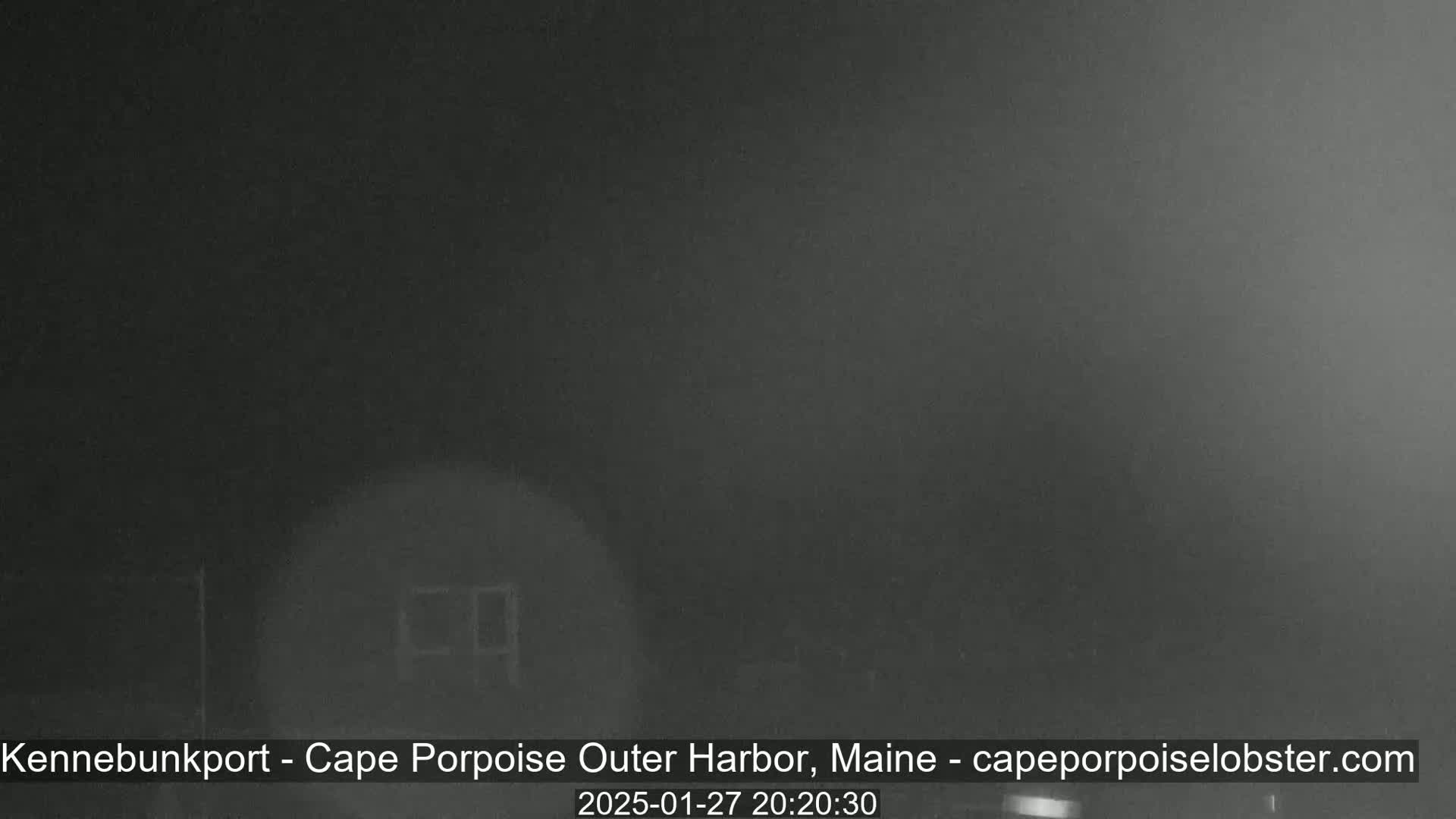 A nighttime, foggy view of a dimly lit structure.