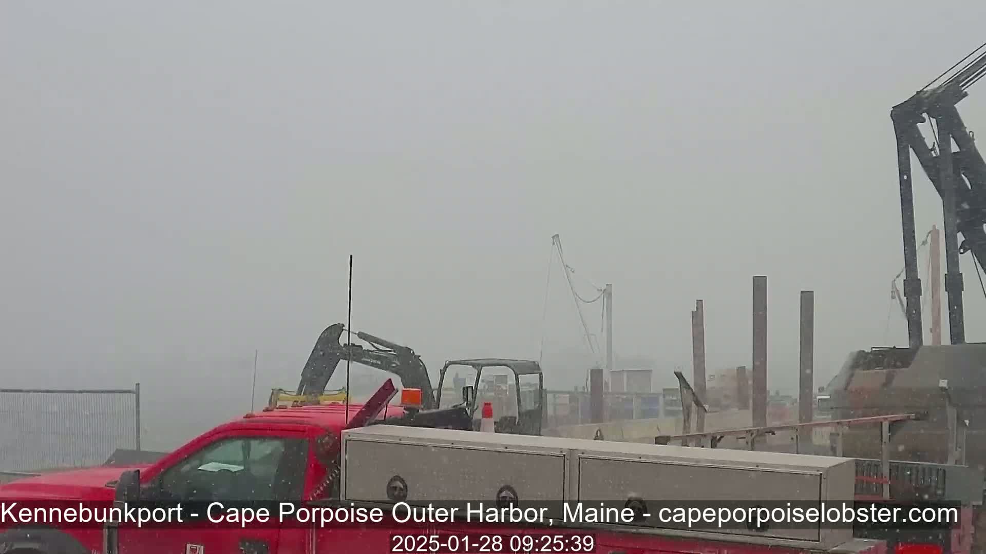 A red truck and construction equipment are partially visible in heavy snowfall.