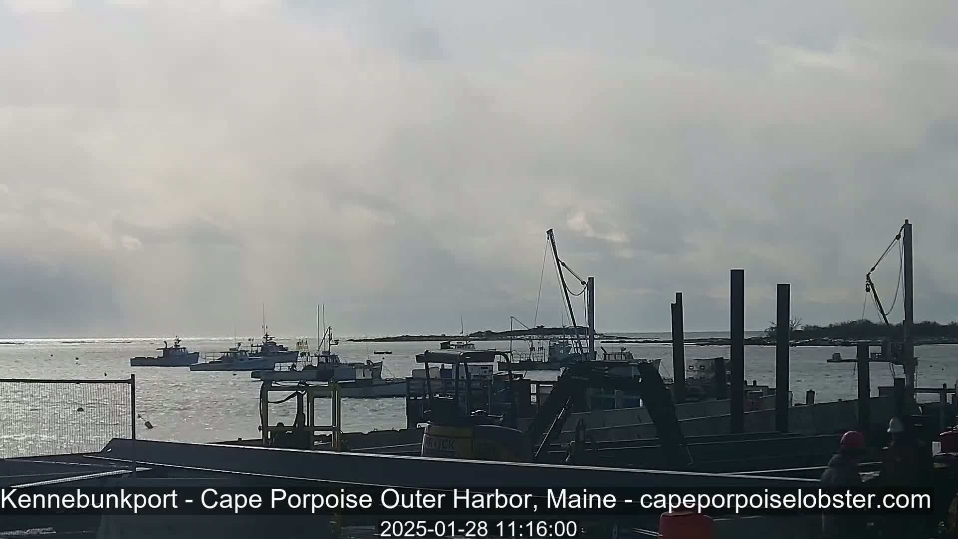 Several fishing boats are moored in a harbor under a cloudy sky.
