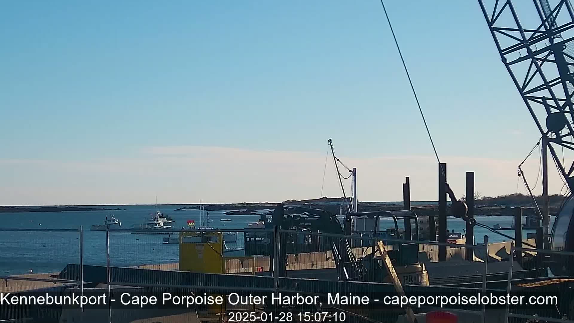 A harbor with several boats, construction equipment, and a crane under a clear blue sky.