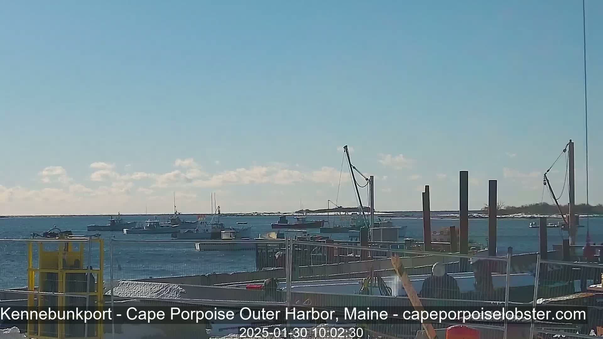 Several fishing boats are in a harbor on a partly sunny day.