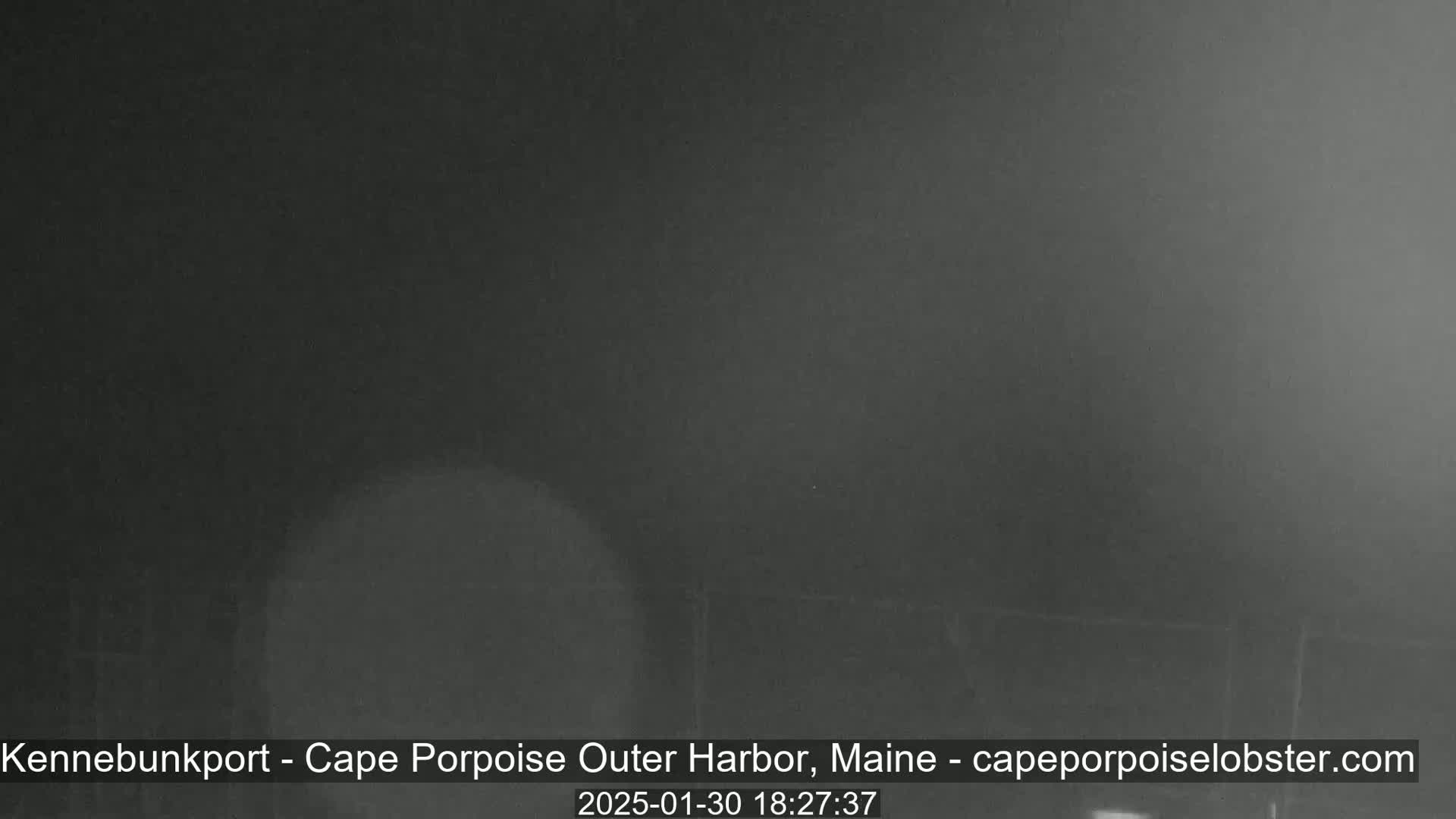 A dark, blurry image shows a mostly obscured view of an outdoor nighttime scene under foggy or hazy conditions.
