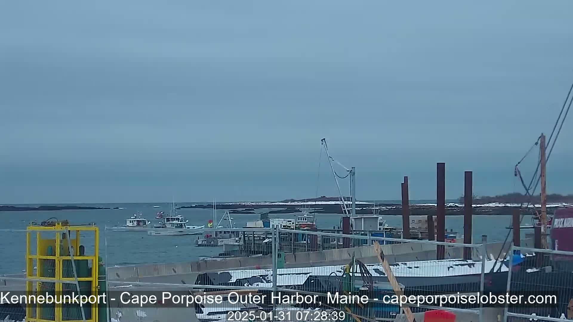 Several fishing boats are moored near a harbor under an overcast sky.