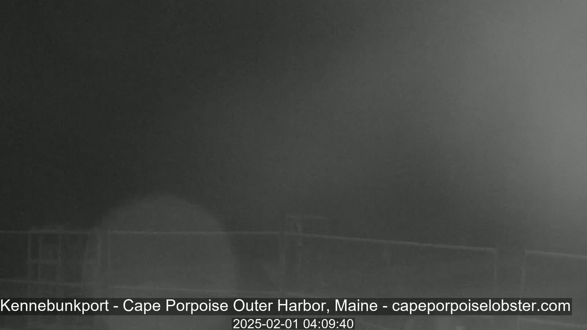 A dark, foggy scene shows a low fence in the foreground.