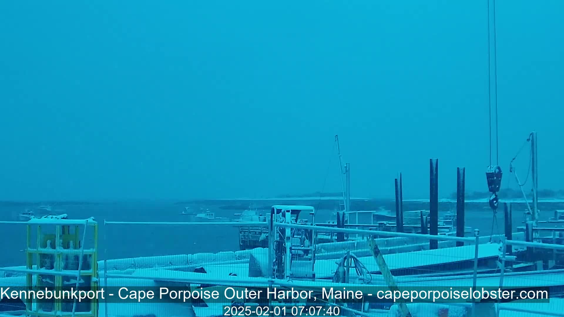 A snow-covered harbor scene shows boats in the water and snow-covered docks and equipment.