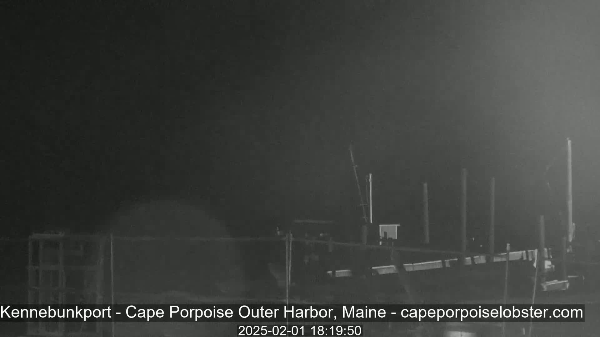 A nighttime, low-visibility view of a harbor with several pilings and what appears to be a dock or similar structure.