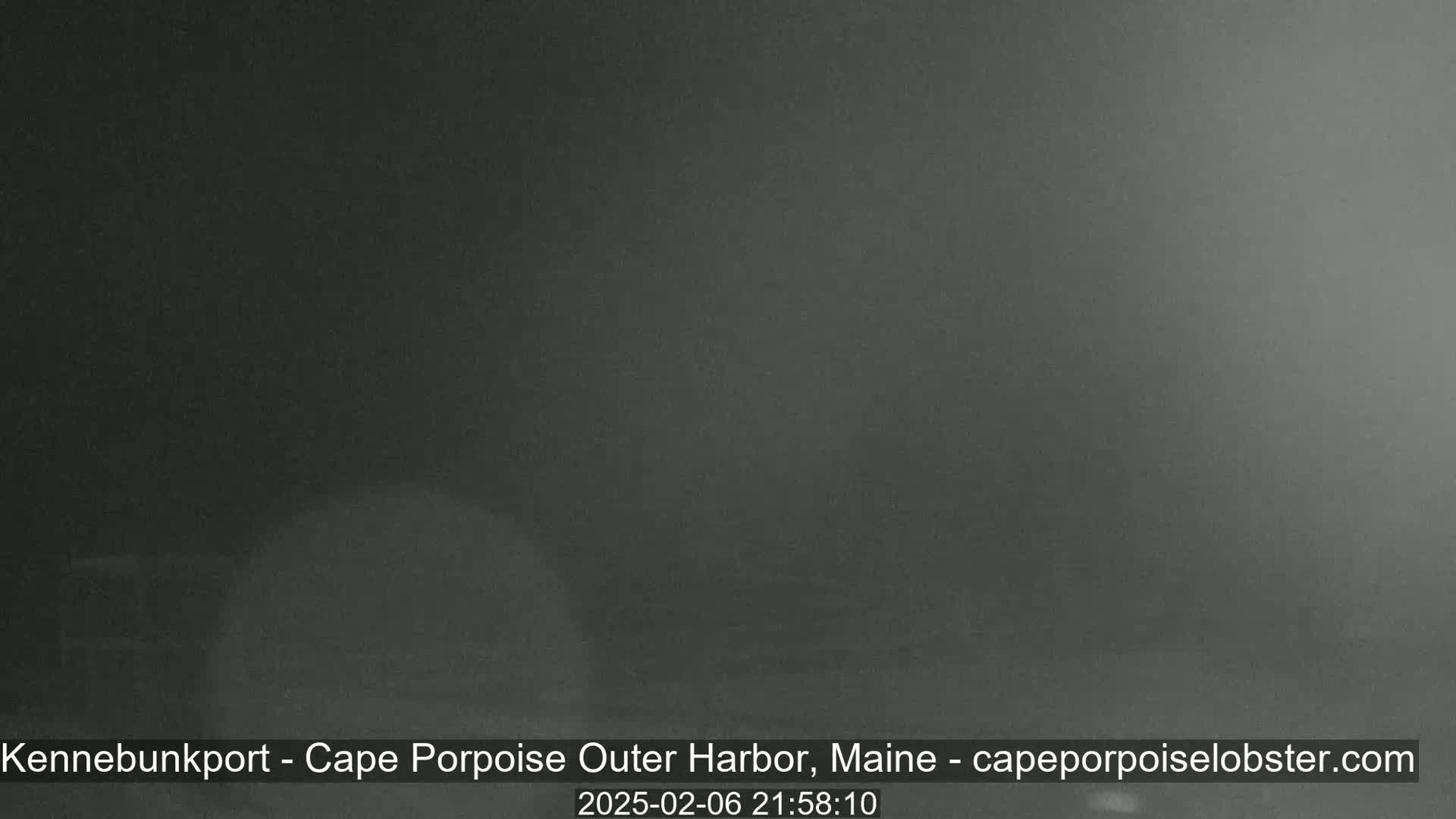 A dark, blurry image shows a nighttime outdoor scene with heavy fog or mist.