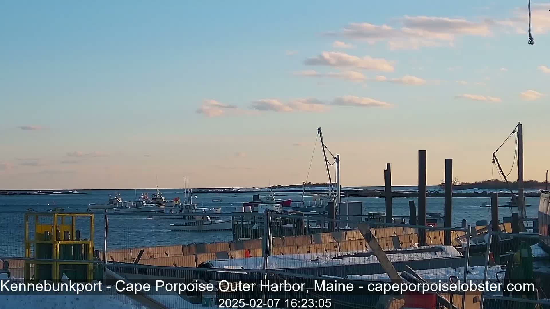 Several fishing boats are moored in a harbor under a partly cloudy sky.