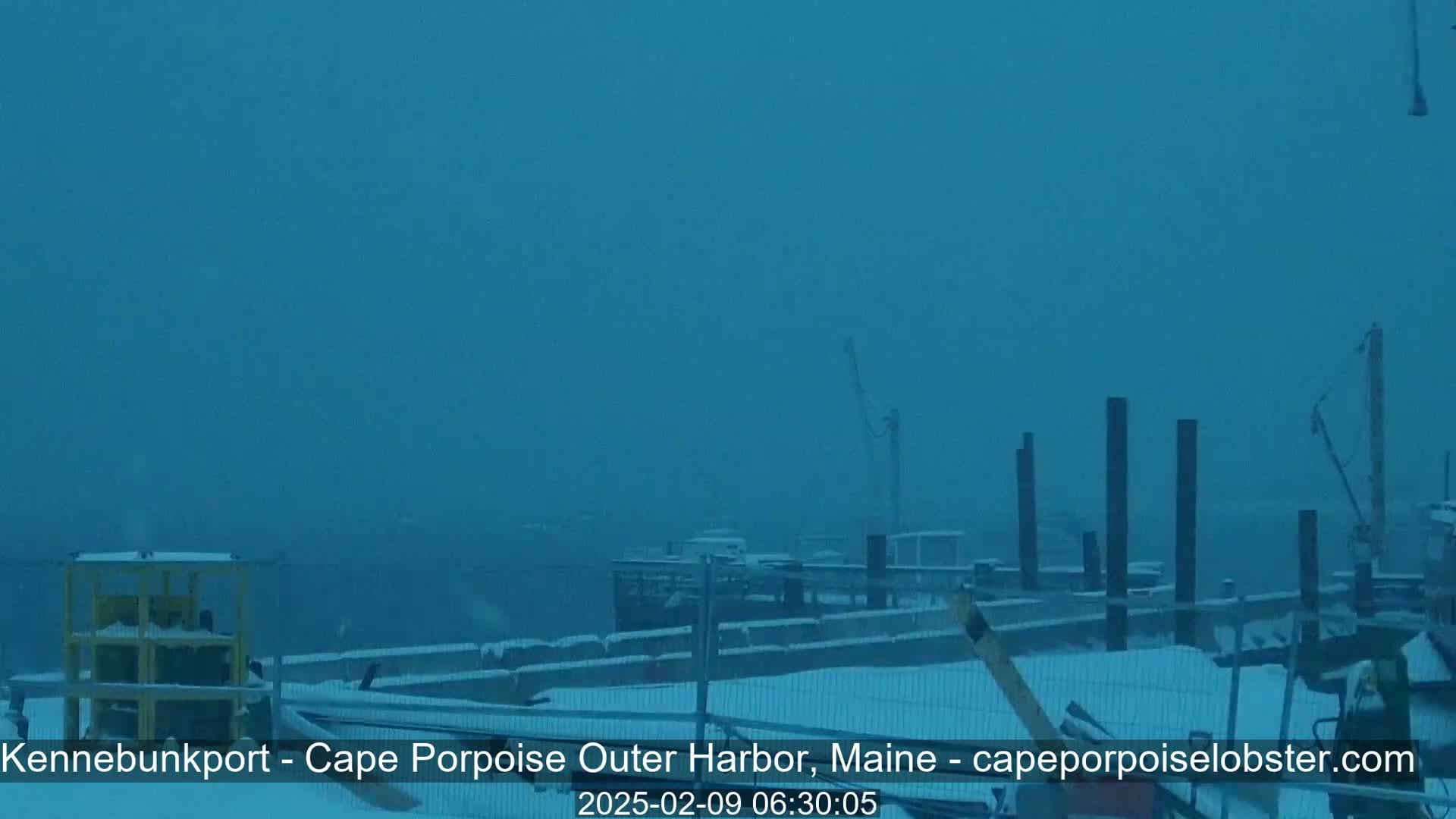 A snow-covered harbor scene is visible, showing a dock with several boats and pilings in the distance under heavy snowfall.
