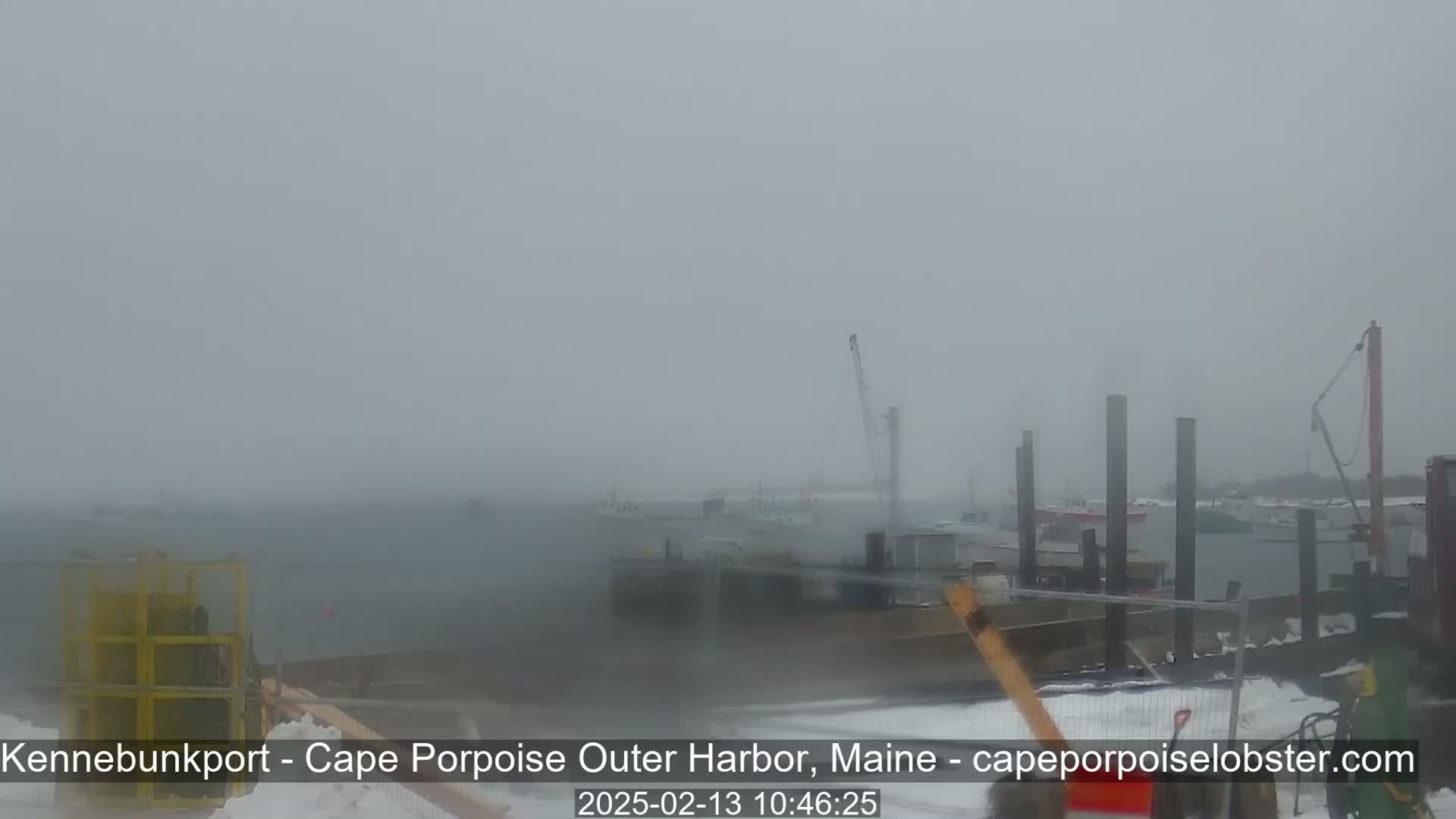 A hazy, snowy scene shows a harbor with boats and docks in the distance.