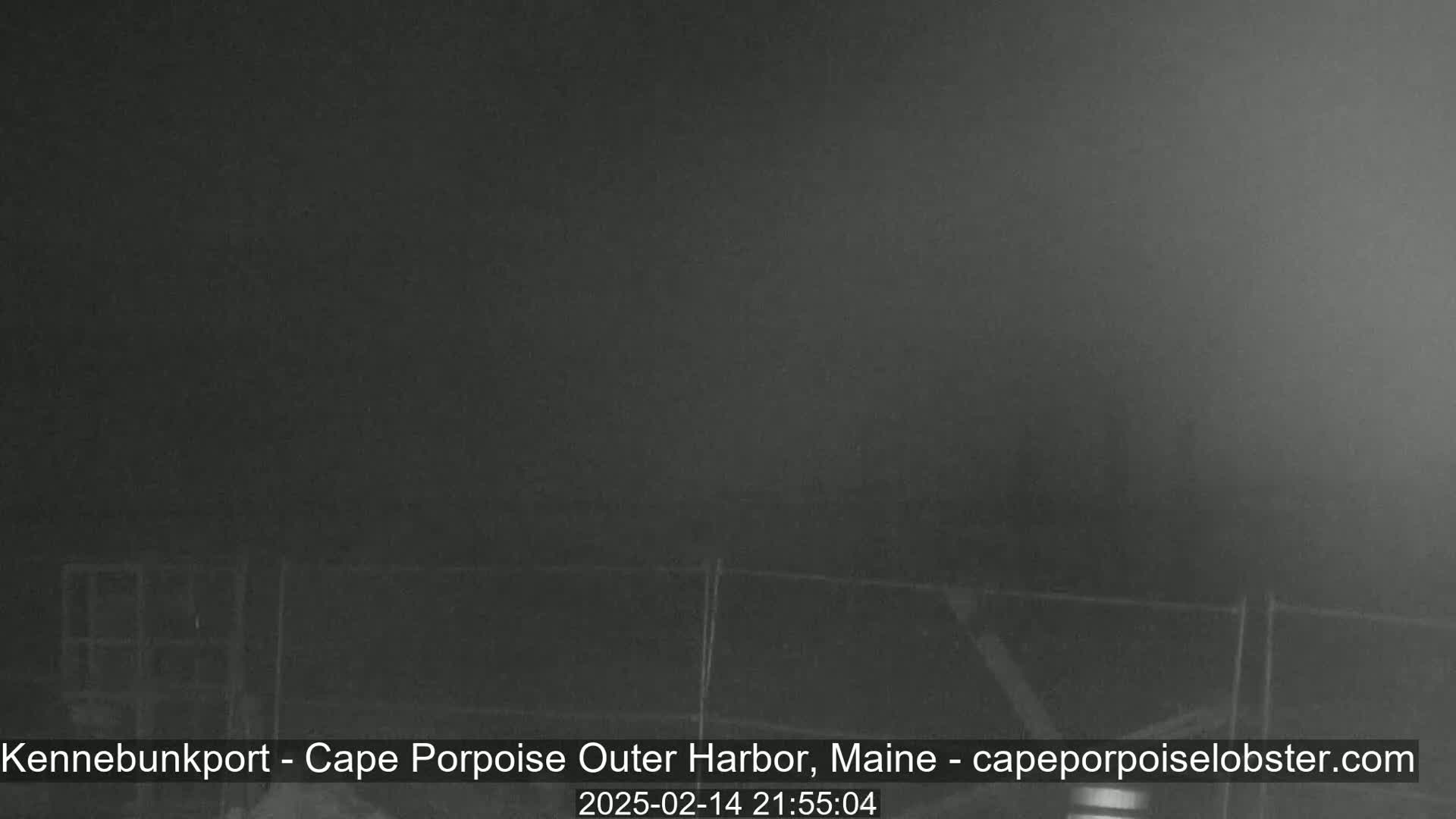 A dark, foggy scene shows a low fence at night.
