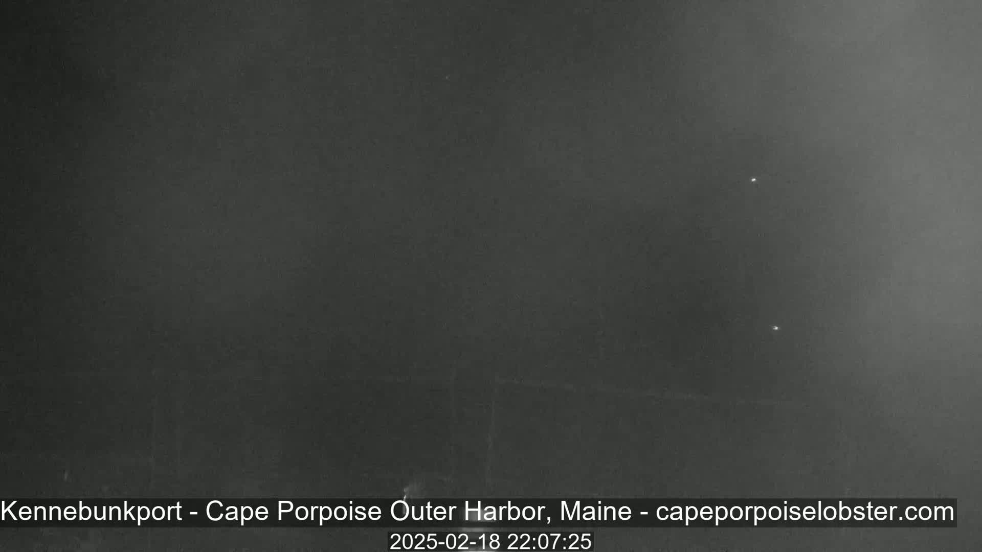 A dark, hazy night scene shows a few faint lights in the distance.