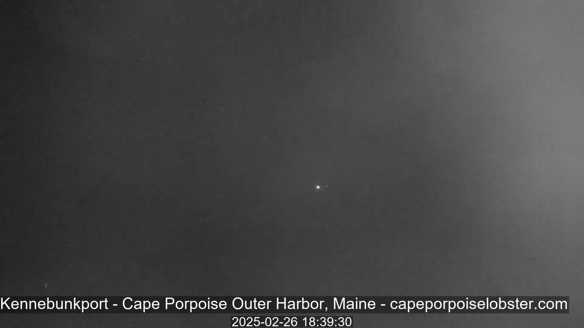 A dark, overcast night scene shows a single, faint light in the distance.