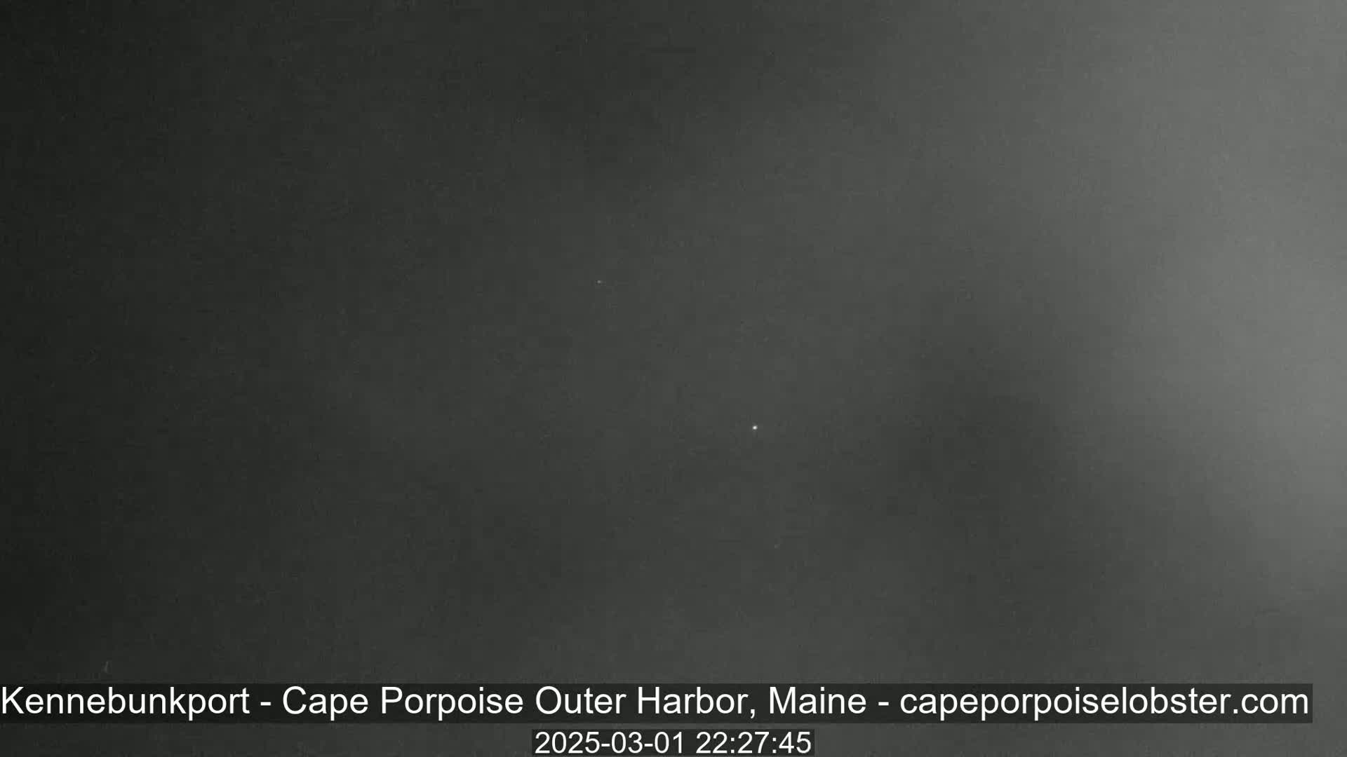 A dark, nighttime image shows a mostly clear sky with a few faint lights visible.