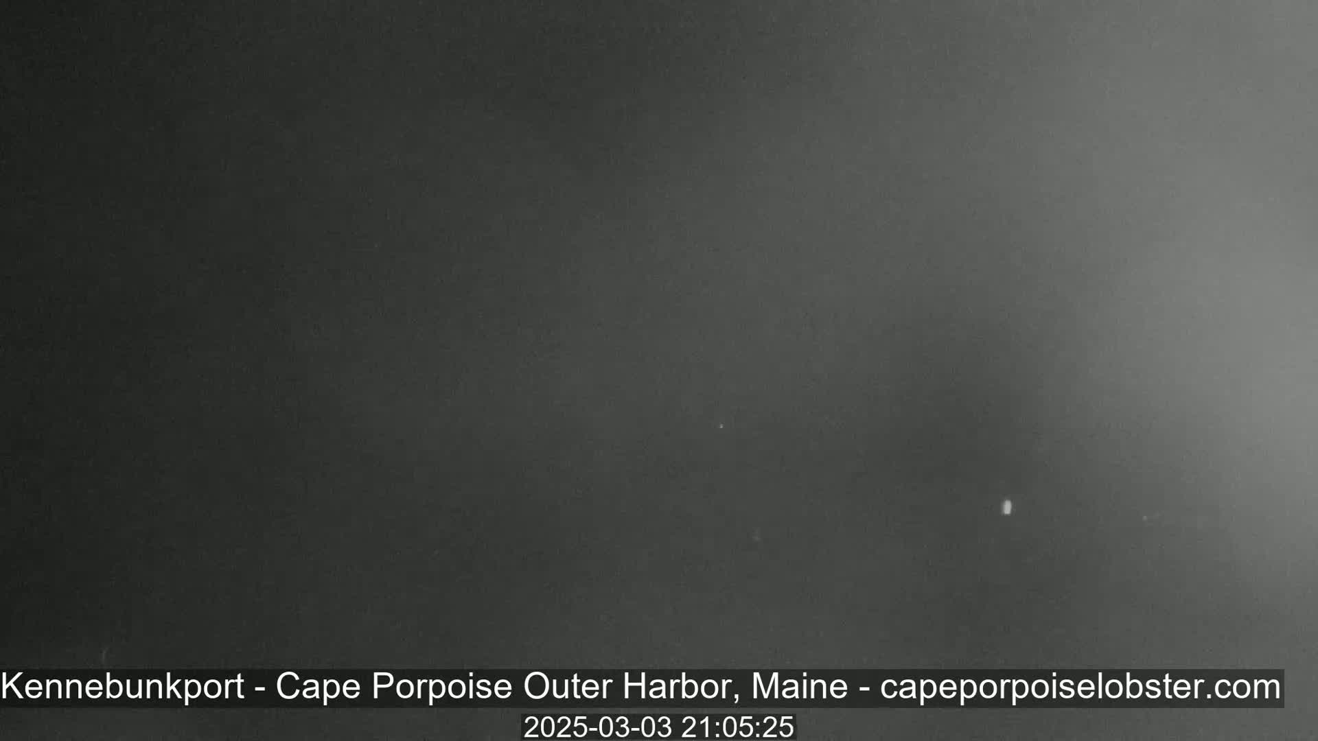 A dark, nighttime image shows a mostly clear sky with a single, faint light visible in the distance.