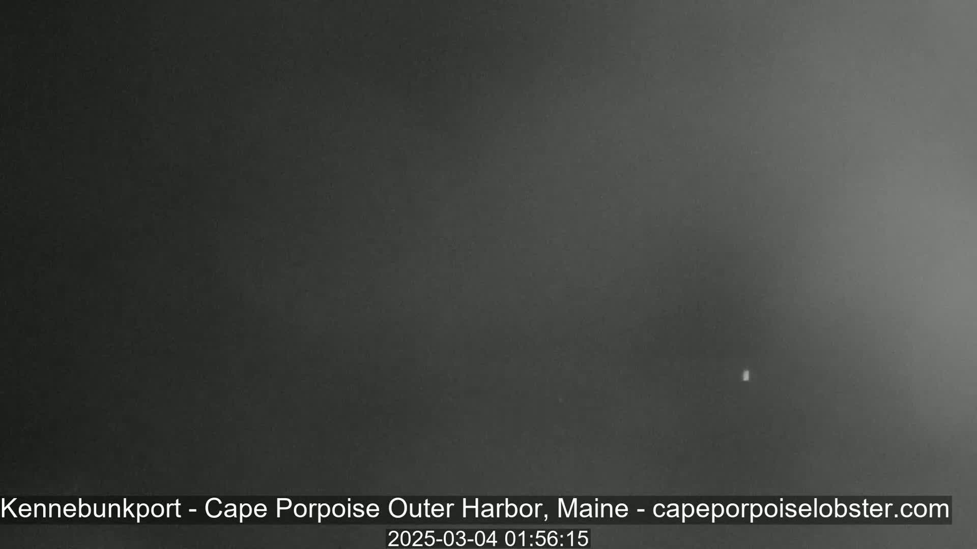 A dark, nighttime image shows a very small, faint light in the center.