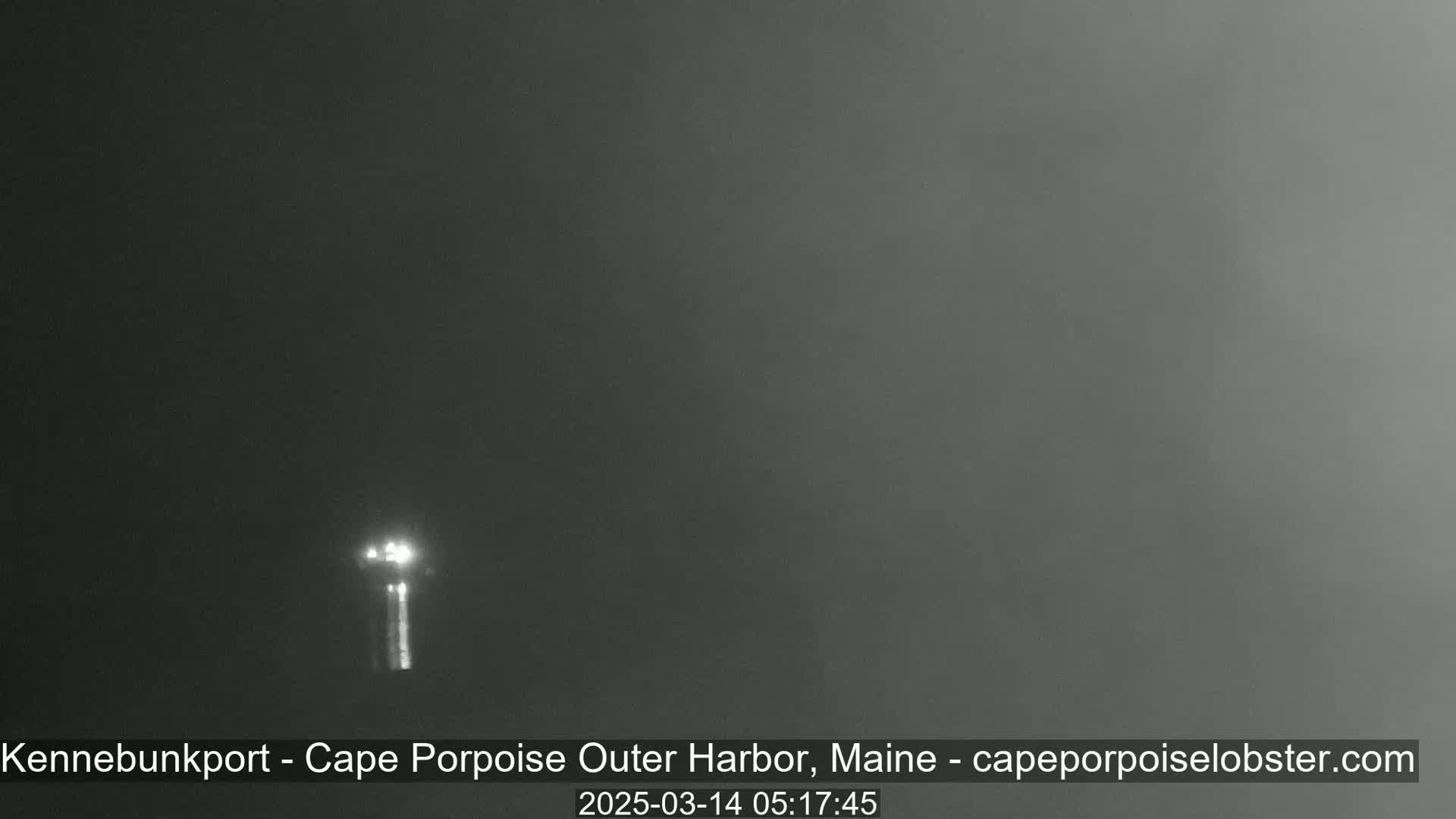 A dimly lit nighttime scene shows a tall structure, possibly a lighthouse, faintly visible in the foggy distance.