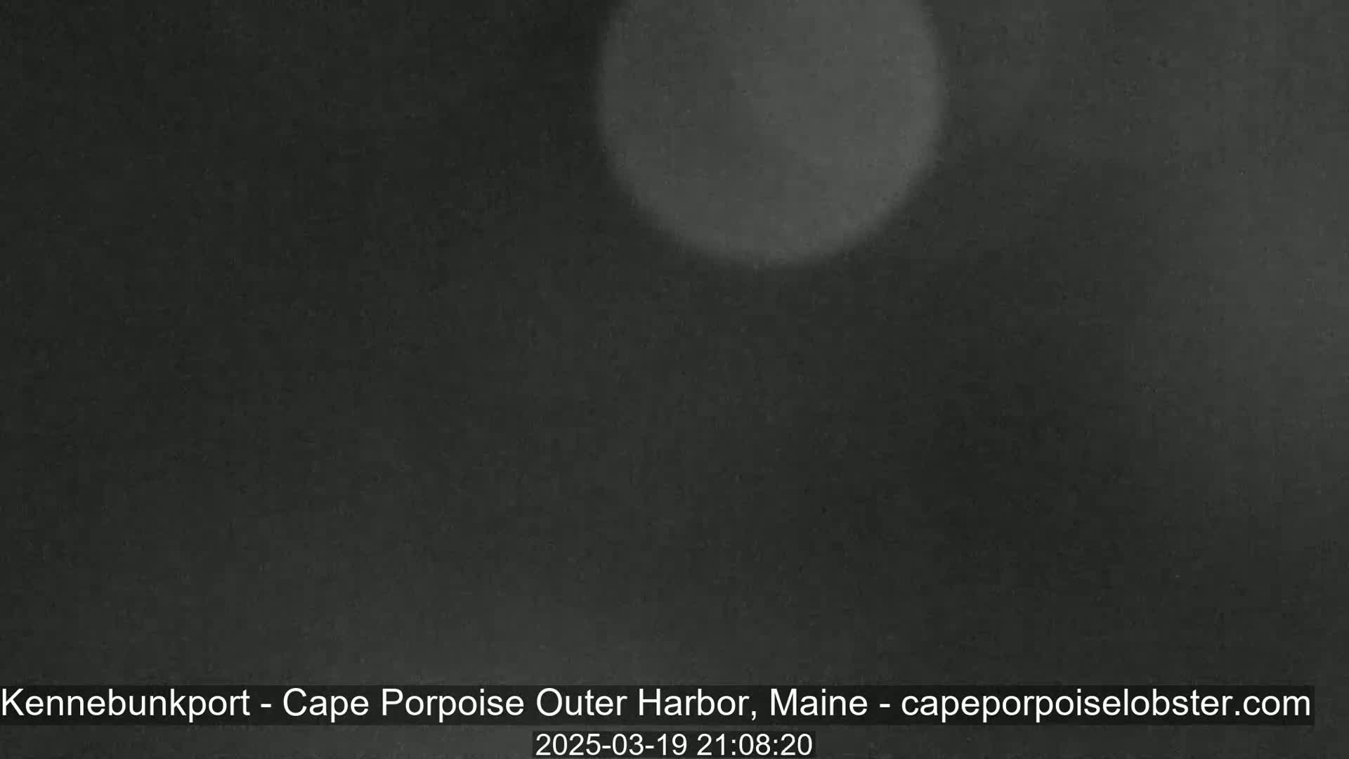 A dark, blurry image shows a nighttime scene with a bright light source out of focus.