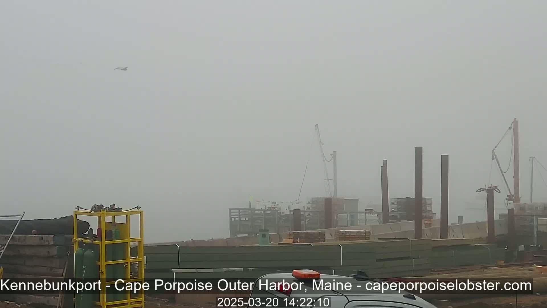 A foggy construction site with cranes and other equipment is visible in the distance.