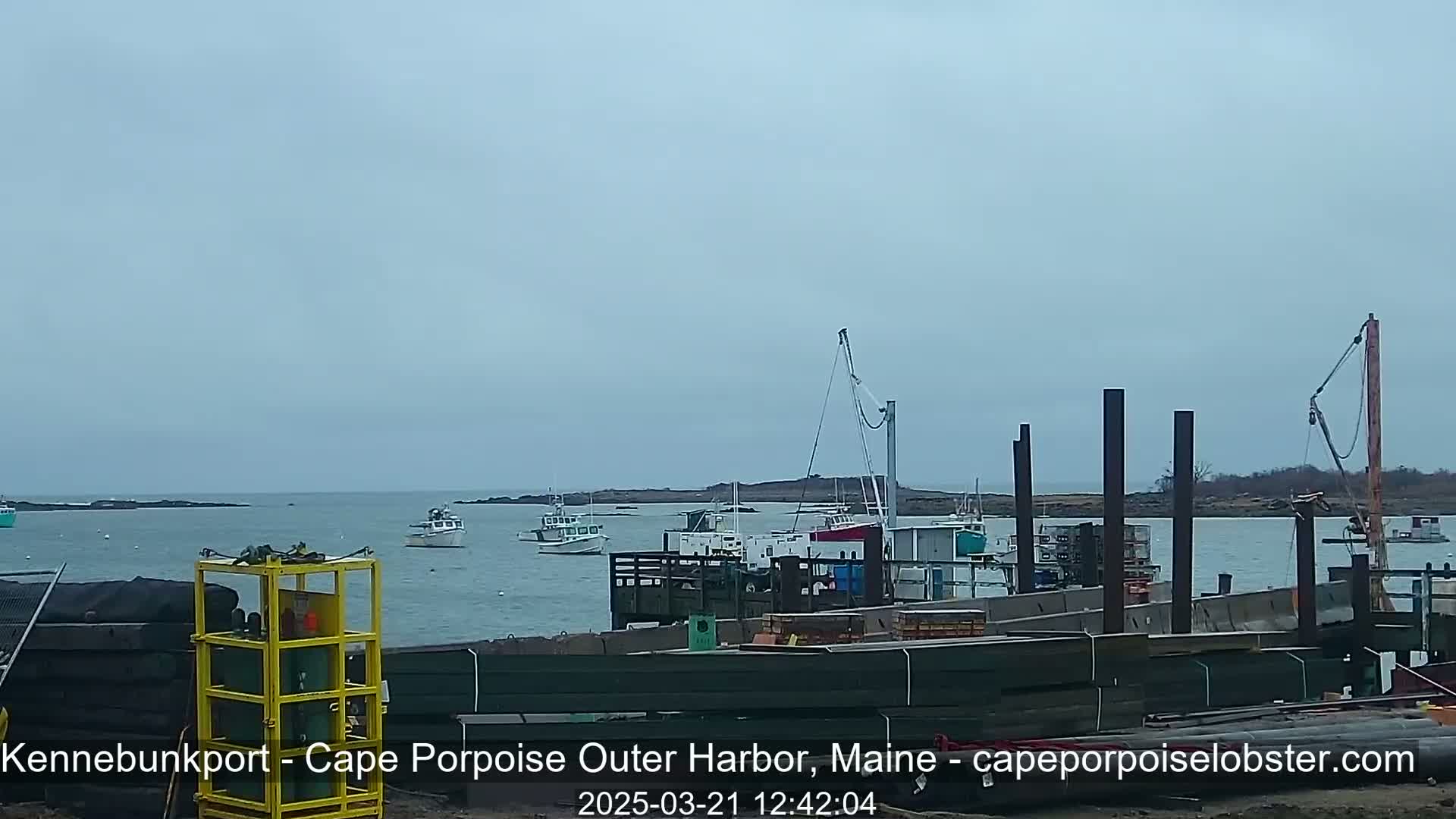Several fishing boats are moored in a harbor under an overcast sky.