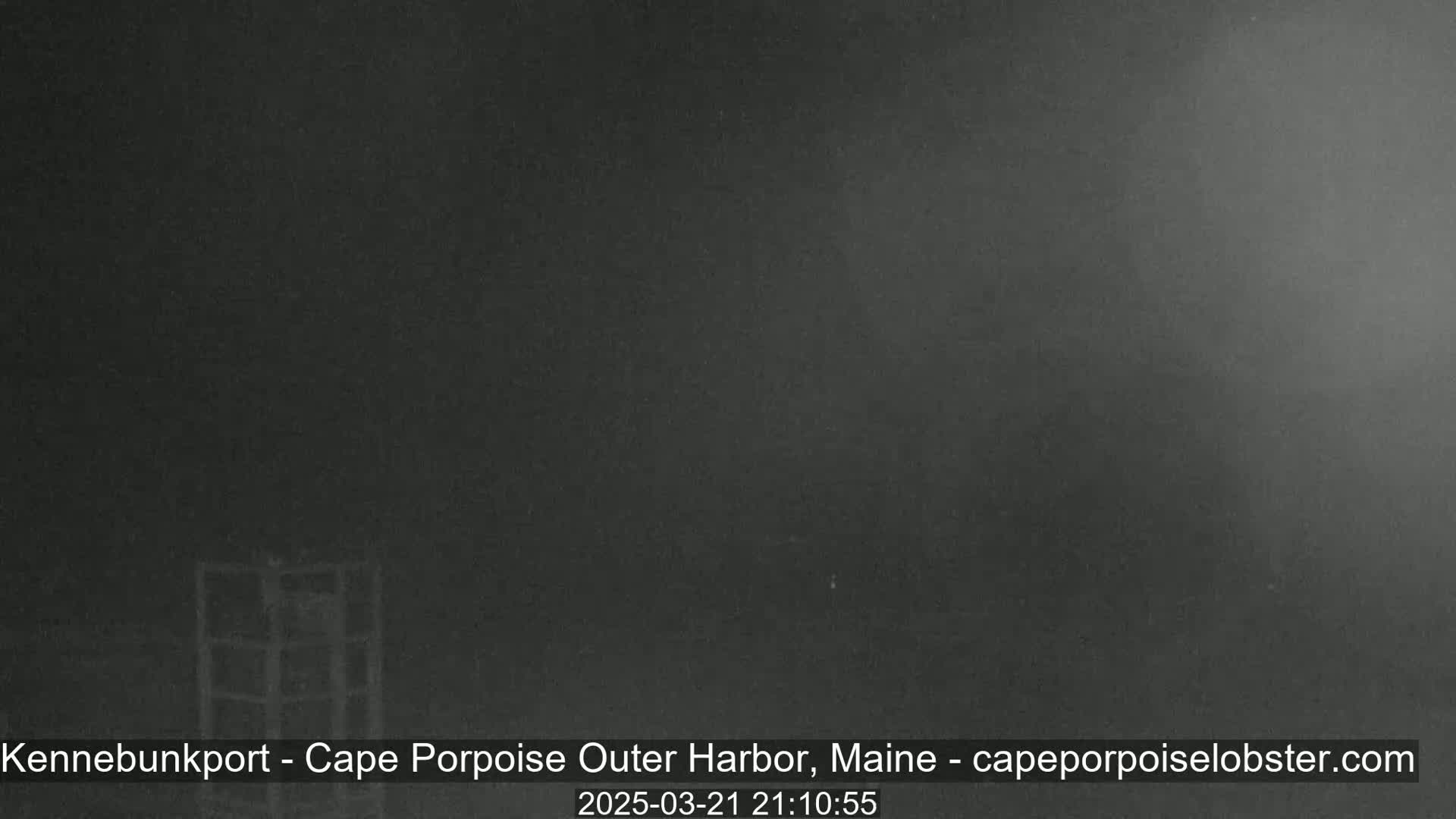 A dark, nighttime scene shows a metal structure in the lower left corner, under a hazy, dark sky.