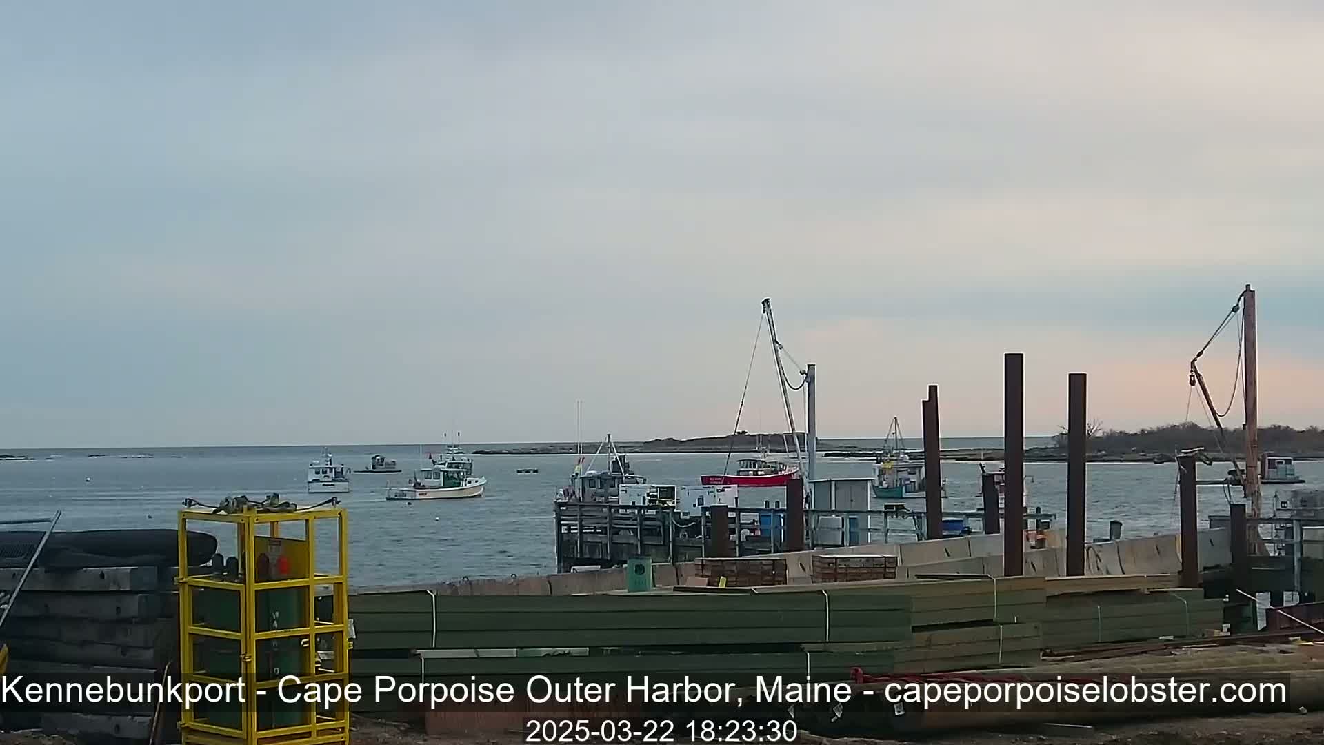Several fishing boats are moored at a harbor under a cloudy sky.