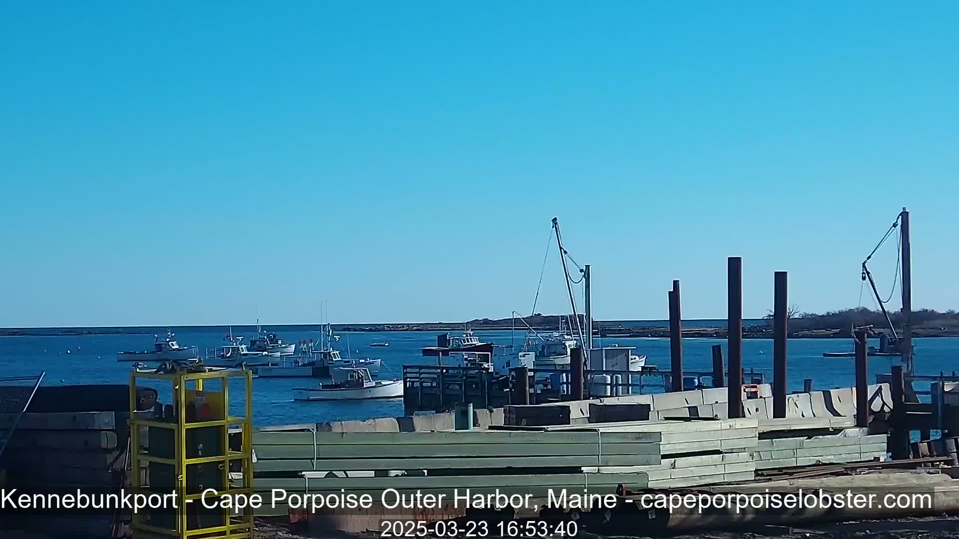 Several fishing boats are moored at a harbor on a clear, sunny day.