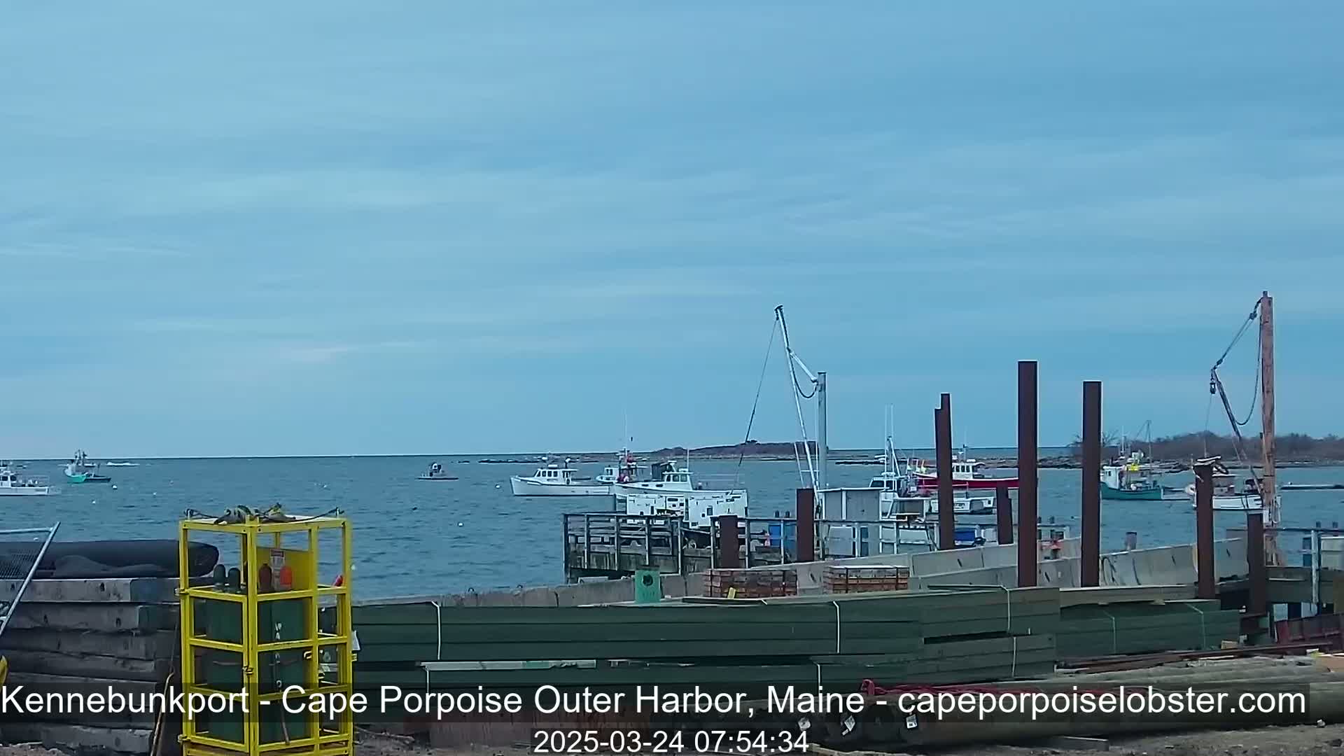 Several fishing boats are moored at a harbor under a mostly clear sky.