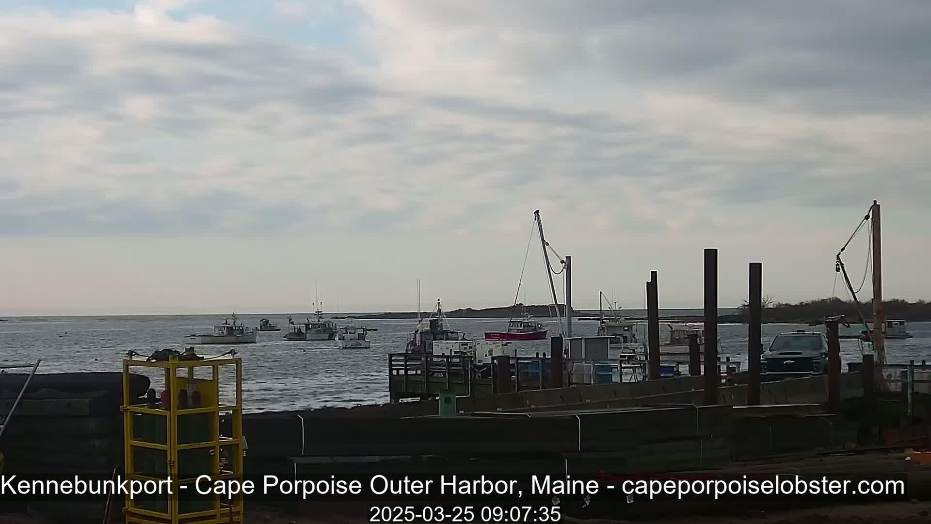 Several fishing boats are moored in a harbor under a cloudy sky.