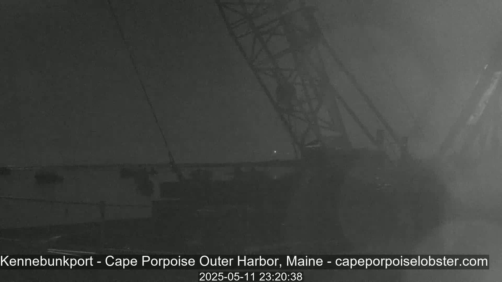 A nighttime, foggy view of a large crane and a portion of a structure, possibly a dock.