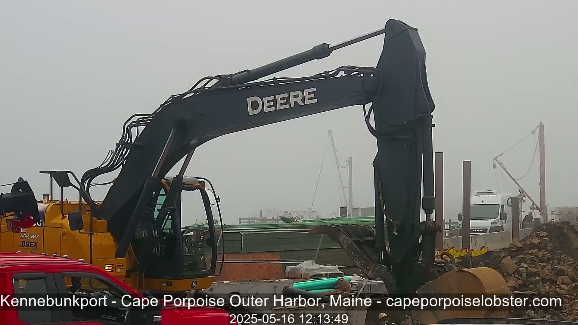 A large Deere excavator is at a construction site on a foggy day.