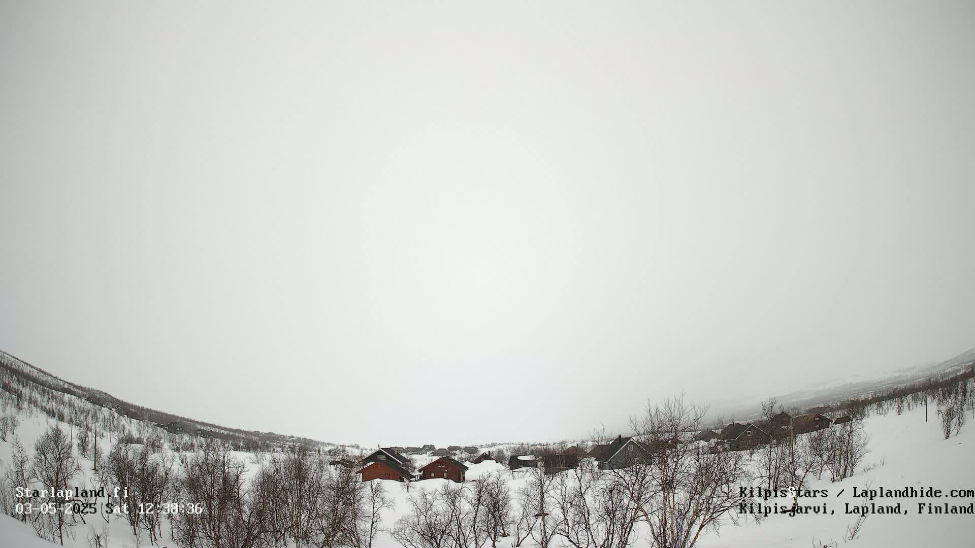 A small snow-covered village sits in a valley under an overcast sky.