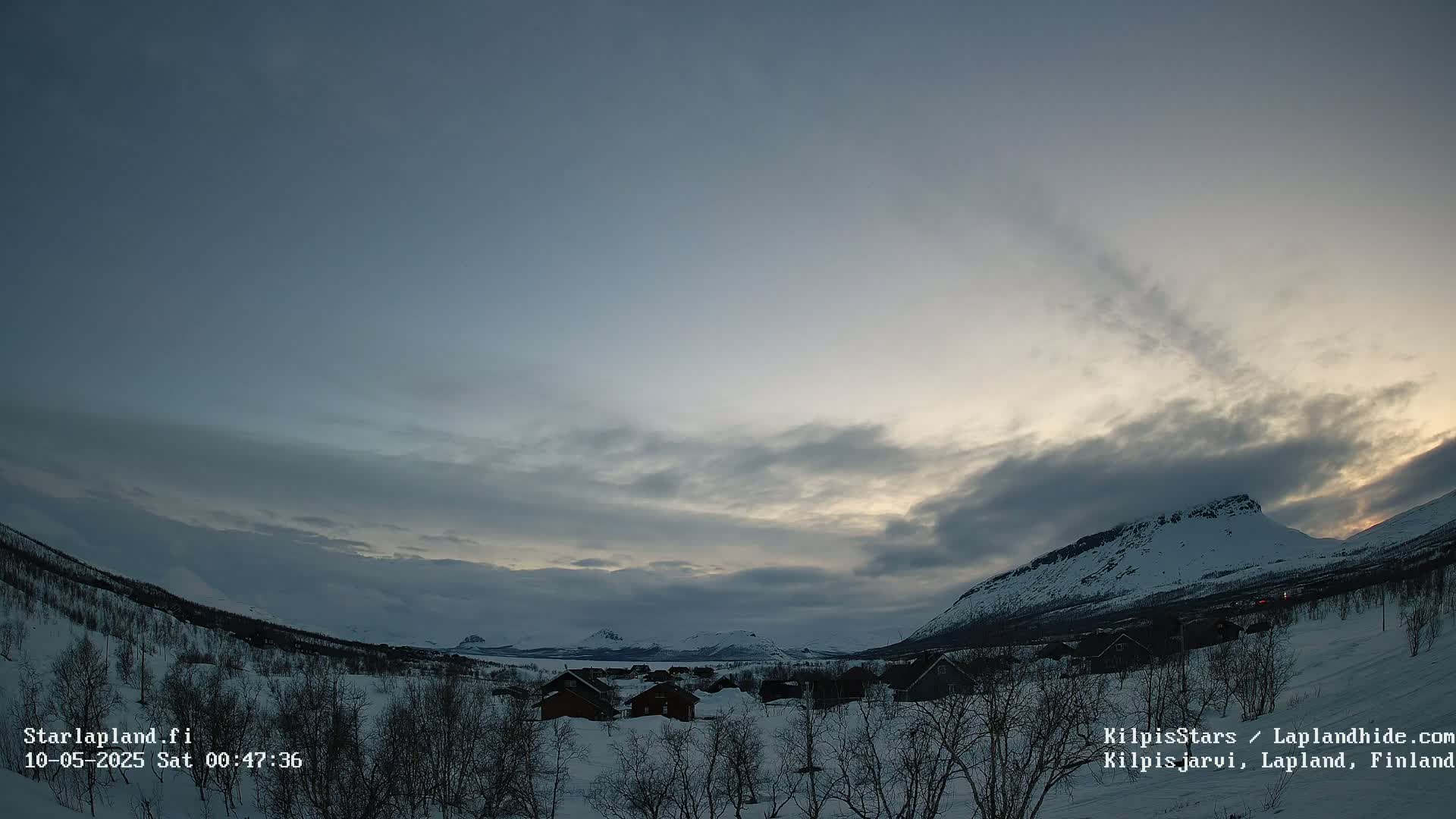 A snowy, mountainous landscape at twilight is visible under a mostly cloudy sky.